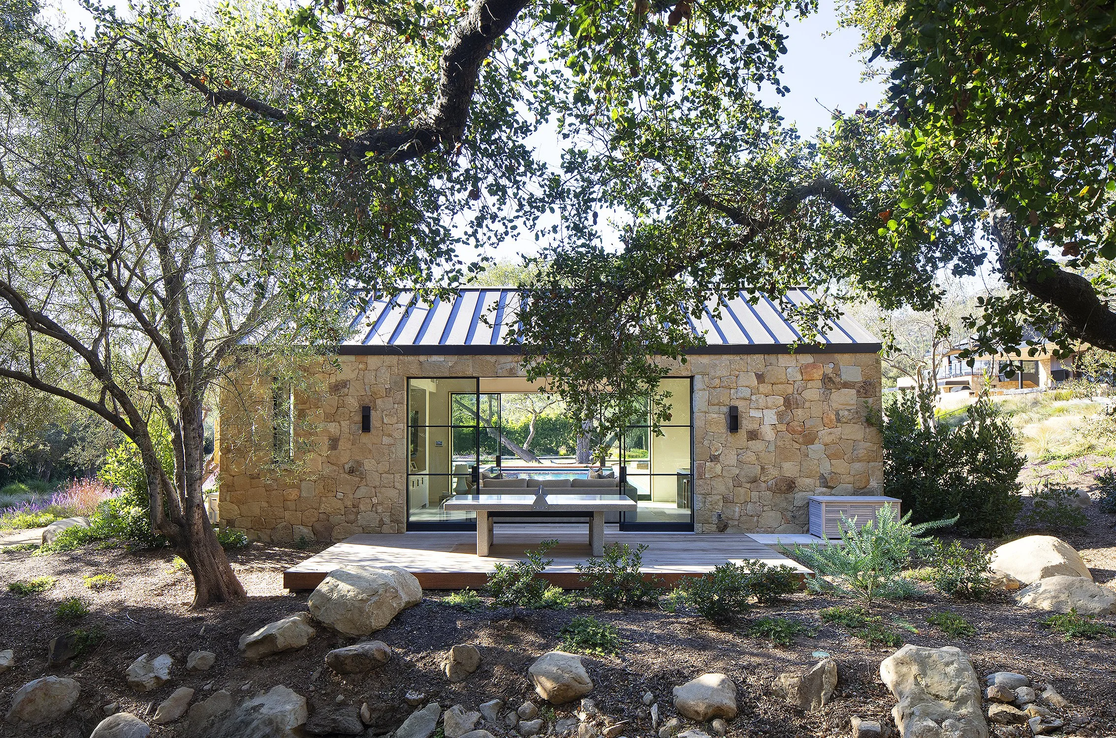 Exterior of pool house built out of stone enclosed in magnificent garden 