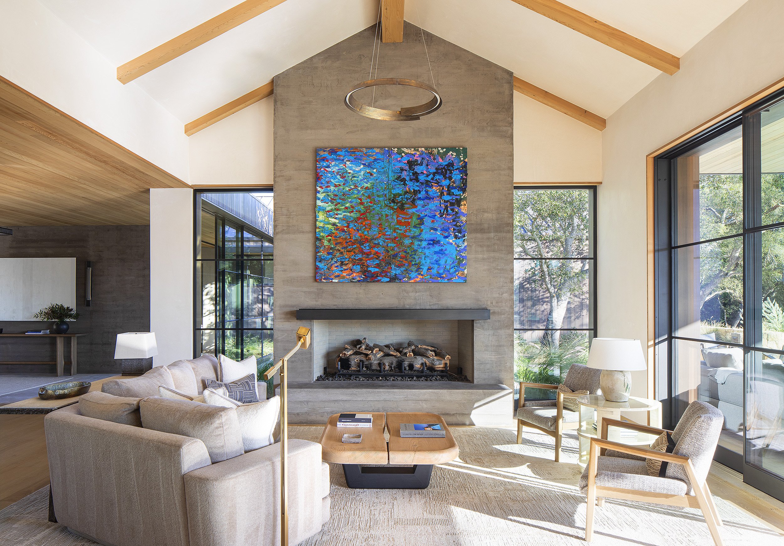 concrete fireplace in sunlit living room with blue painting Montecito California 
