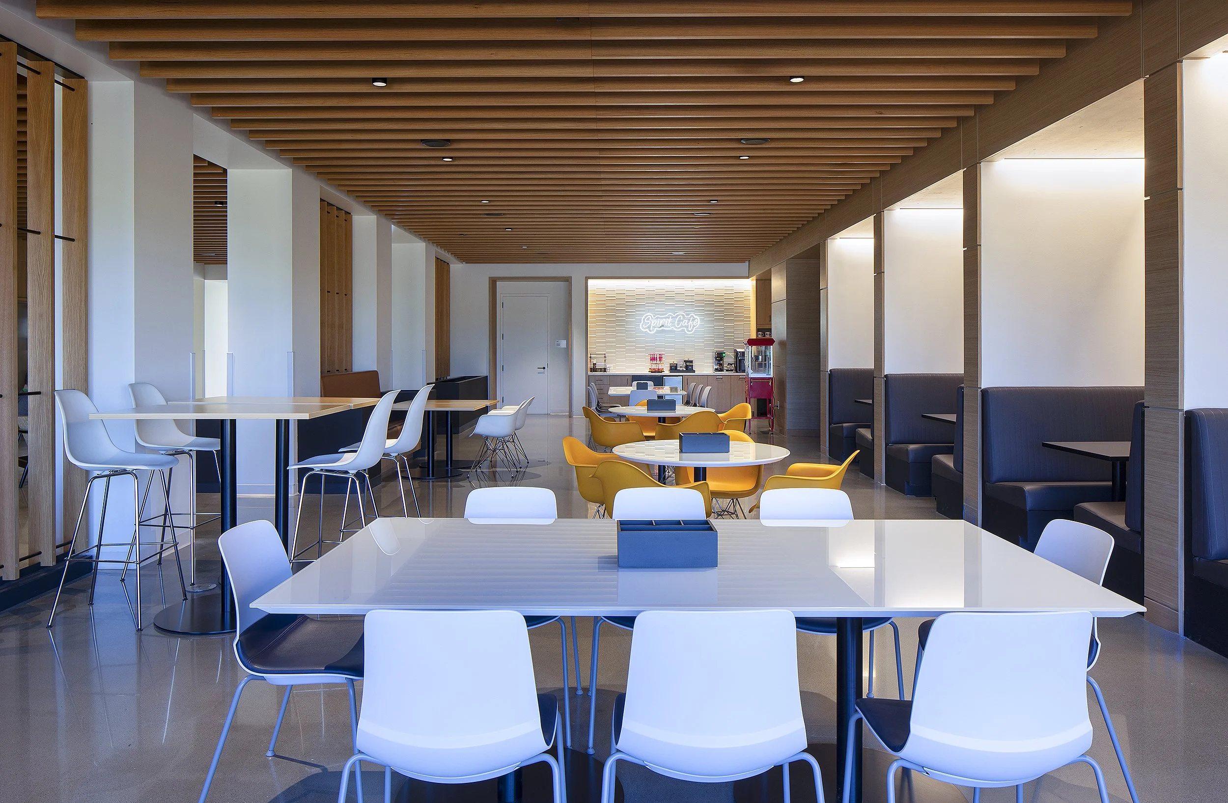 Office break and lunch room with white and yellow chairs at the tables 
