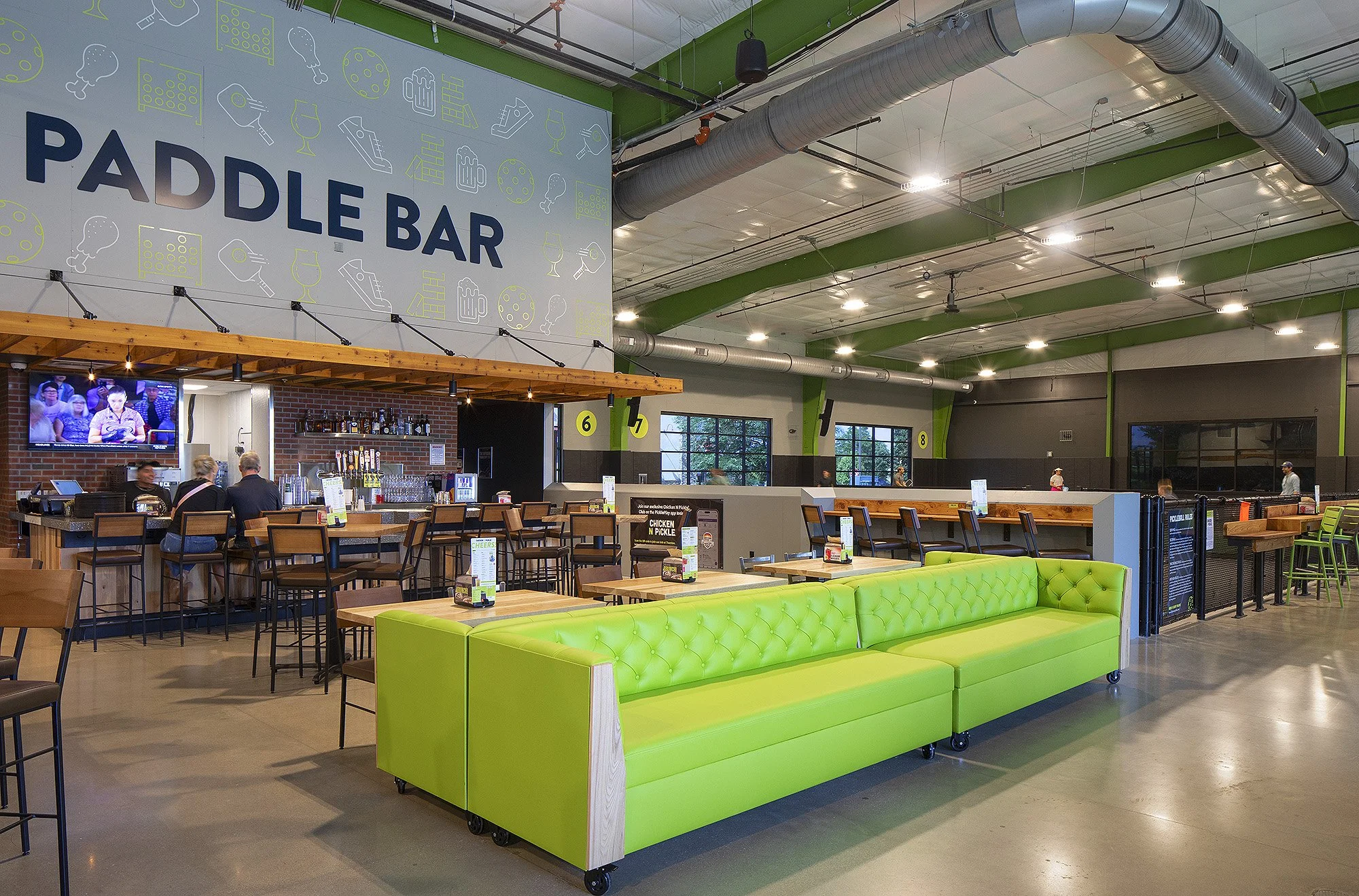 Two people sitting at a bar named the paddle bar at Chicken N Pickle