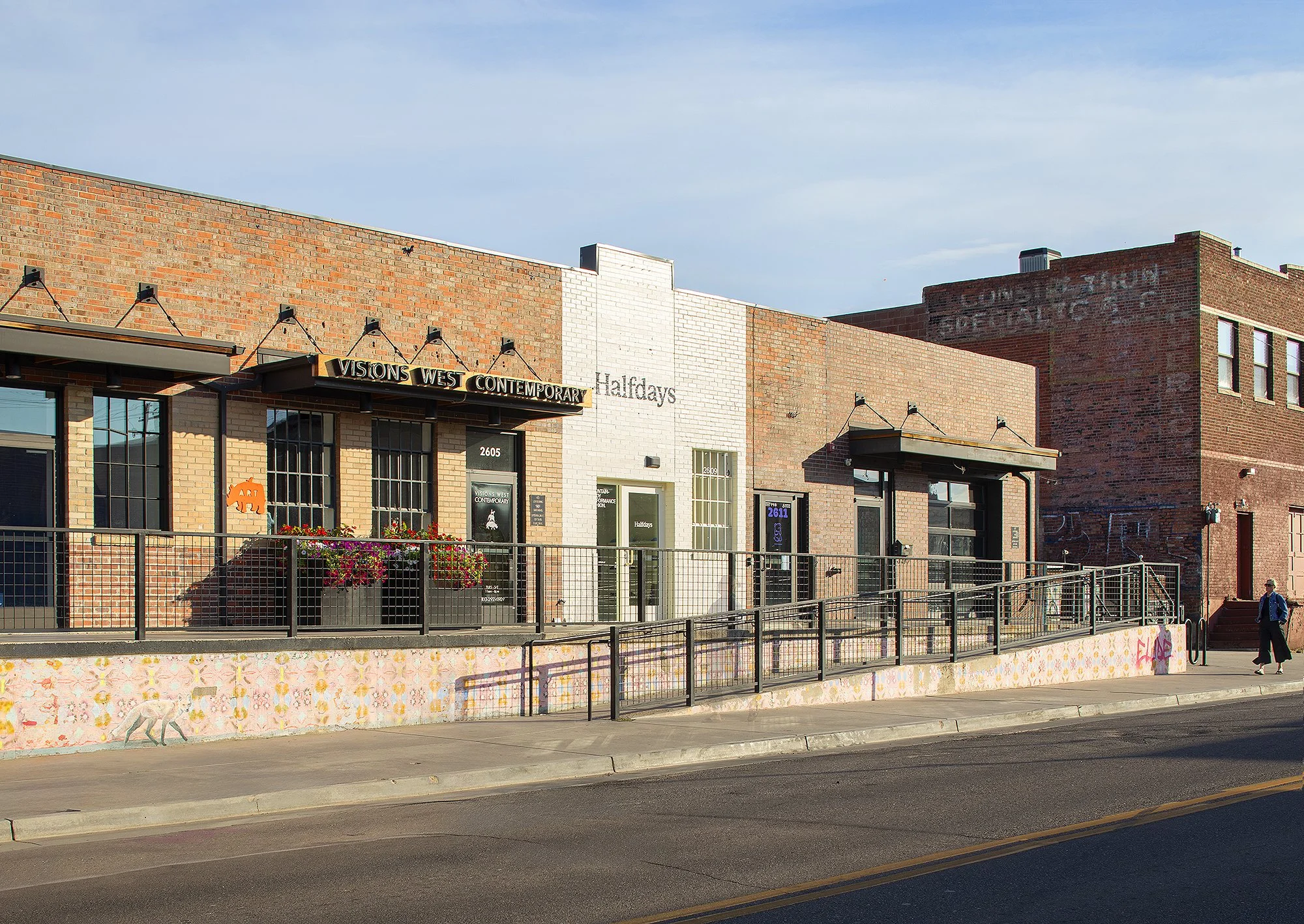Woman infer right with jean jacket walking in front of of brick building in Denver, Colorado