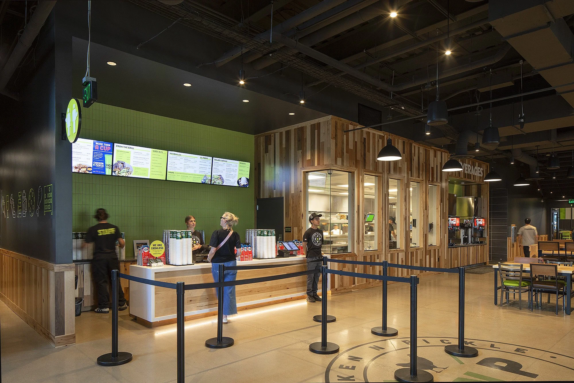 Woman in blue jeans ordering food at counter at Chicken N Pickle