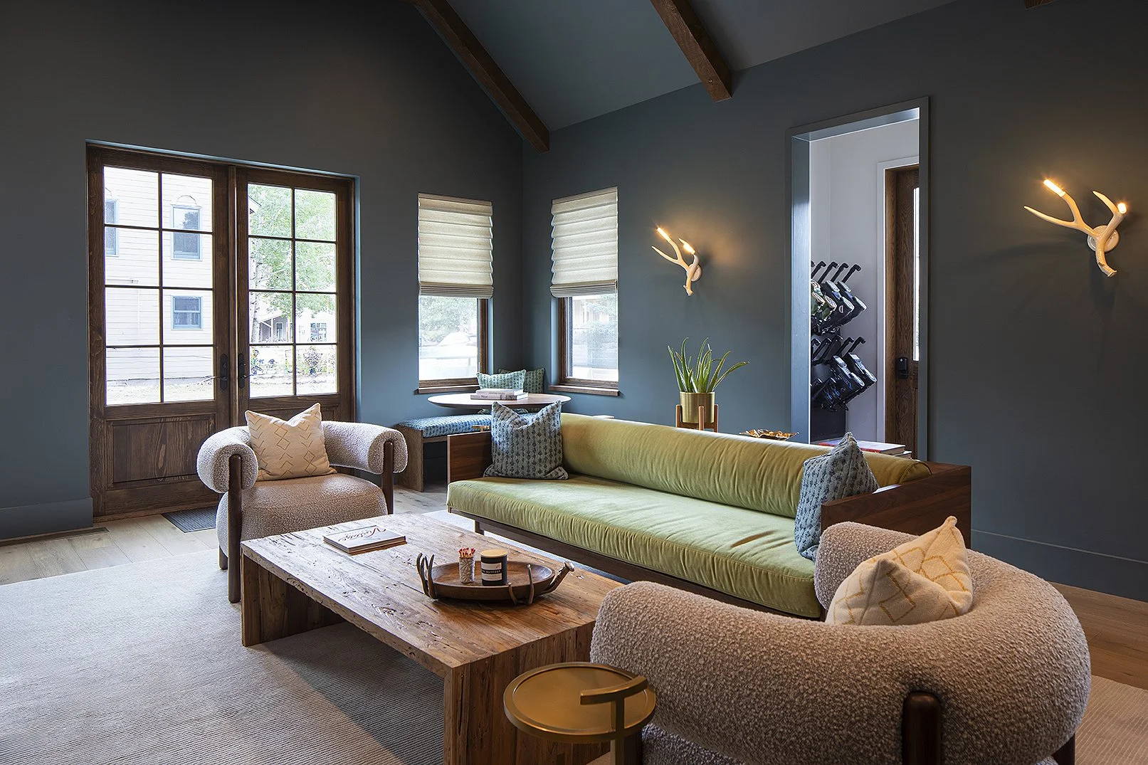 Game room with green couch and green walls with two deer horn sconces 