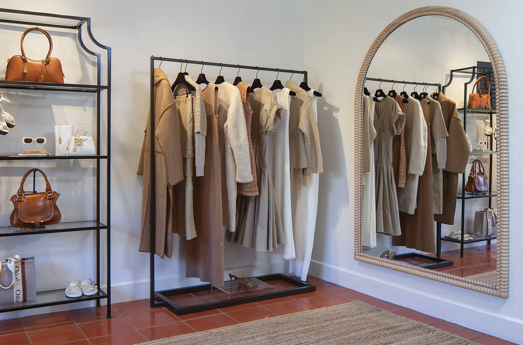 Sacks 5th Avenue showroom with women's dresses displayed on rack and two brown purses to the the right