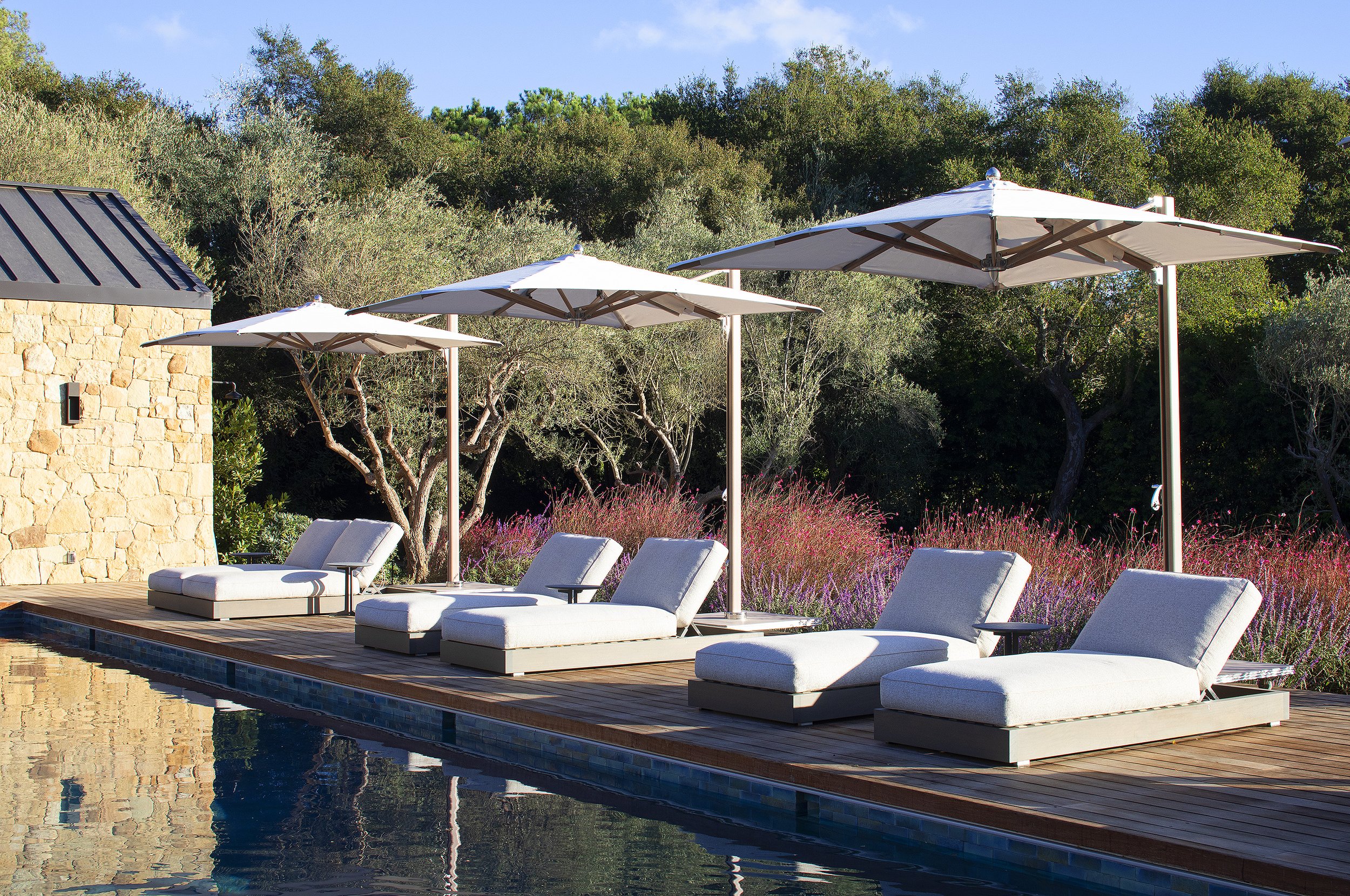 six white lounge chairs with white umbrellas around pool in Montecito California 