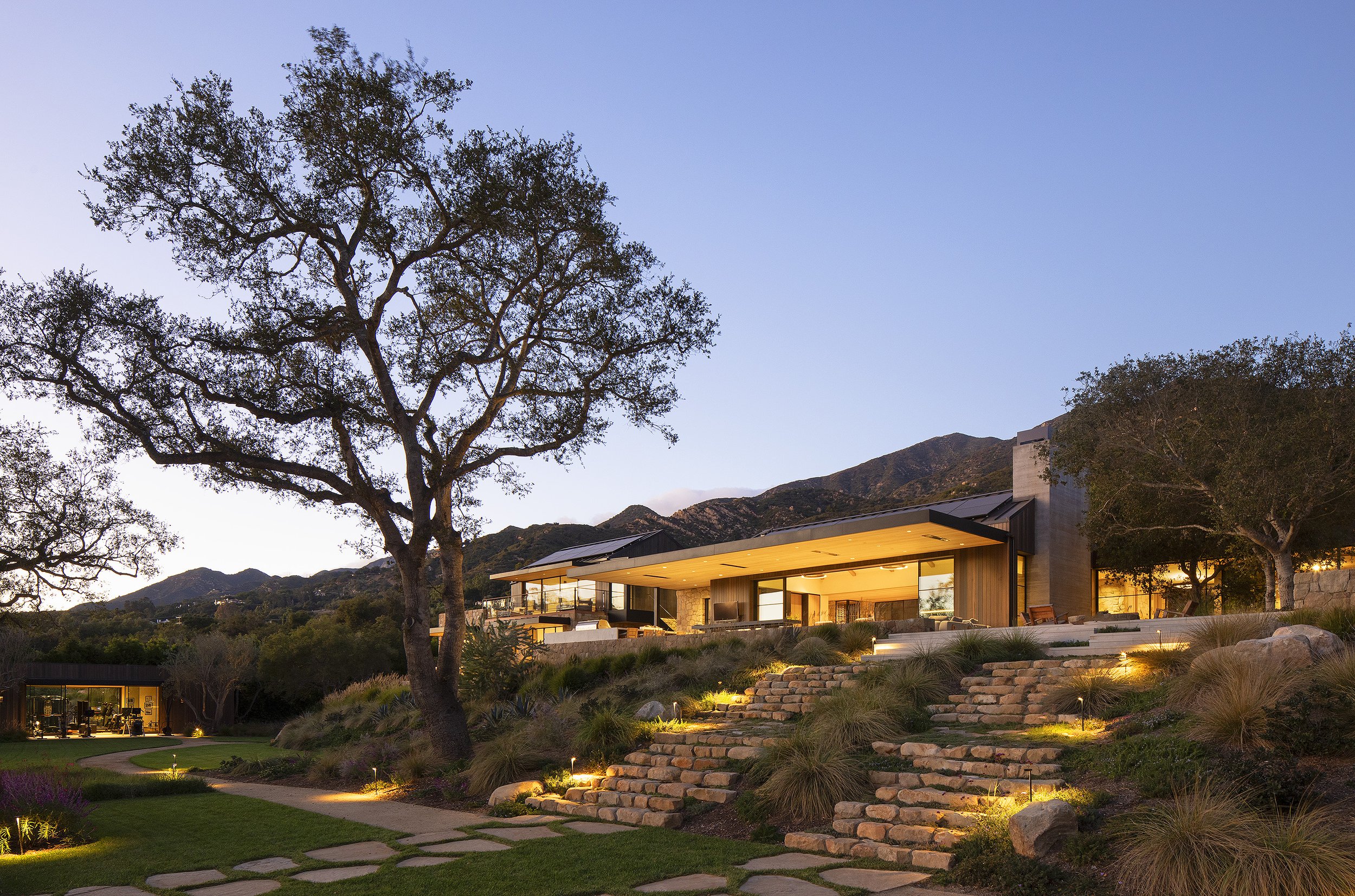 exterior of a Montecito California house at dusk with large tree in front 
