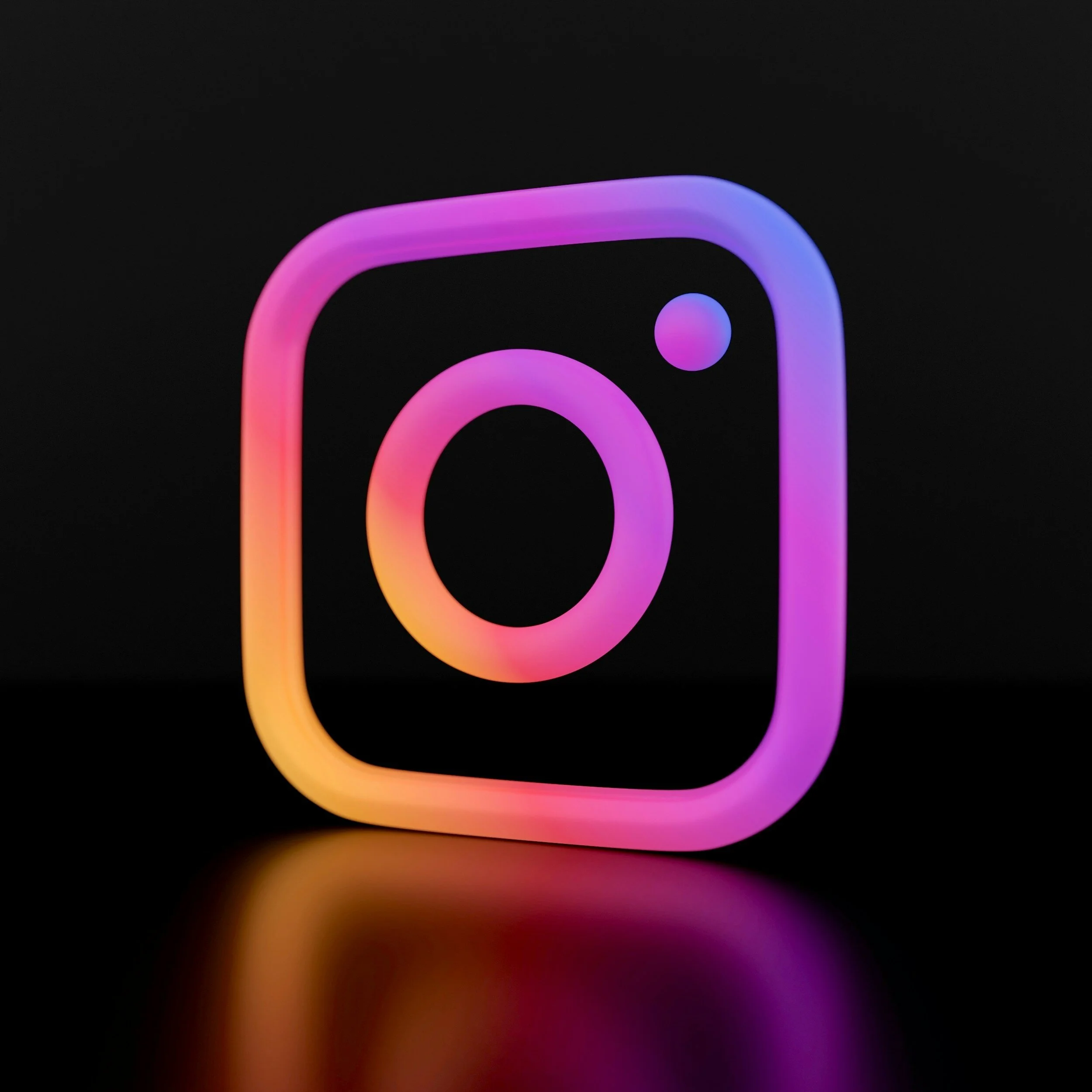 Logo de Instagram con efecto de neón en colores rosa, azul y amarillo sobre fondo negro.