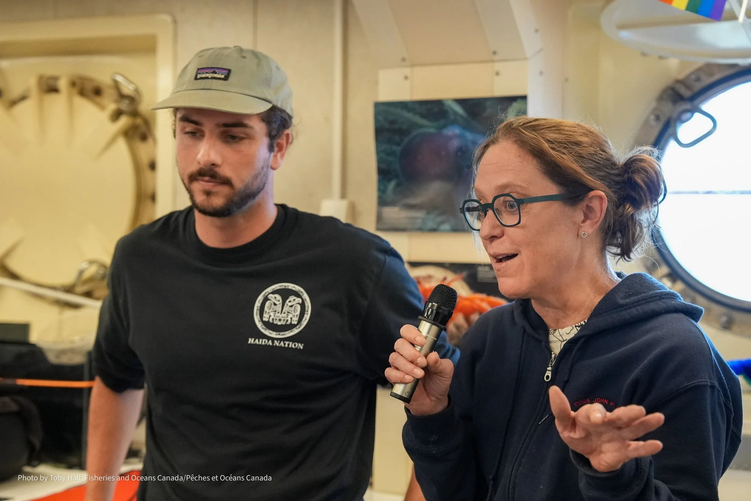 Aiden Schubert (left; CHN) and Rachel Lauer (right; University of Calgary) during a ship2shore event.  Dr Rachel Lauer studies submarine hydrogeology - the movement of fluids in the oceanic crust beneath the seafloor. She is studying the fluid flow a