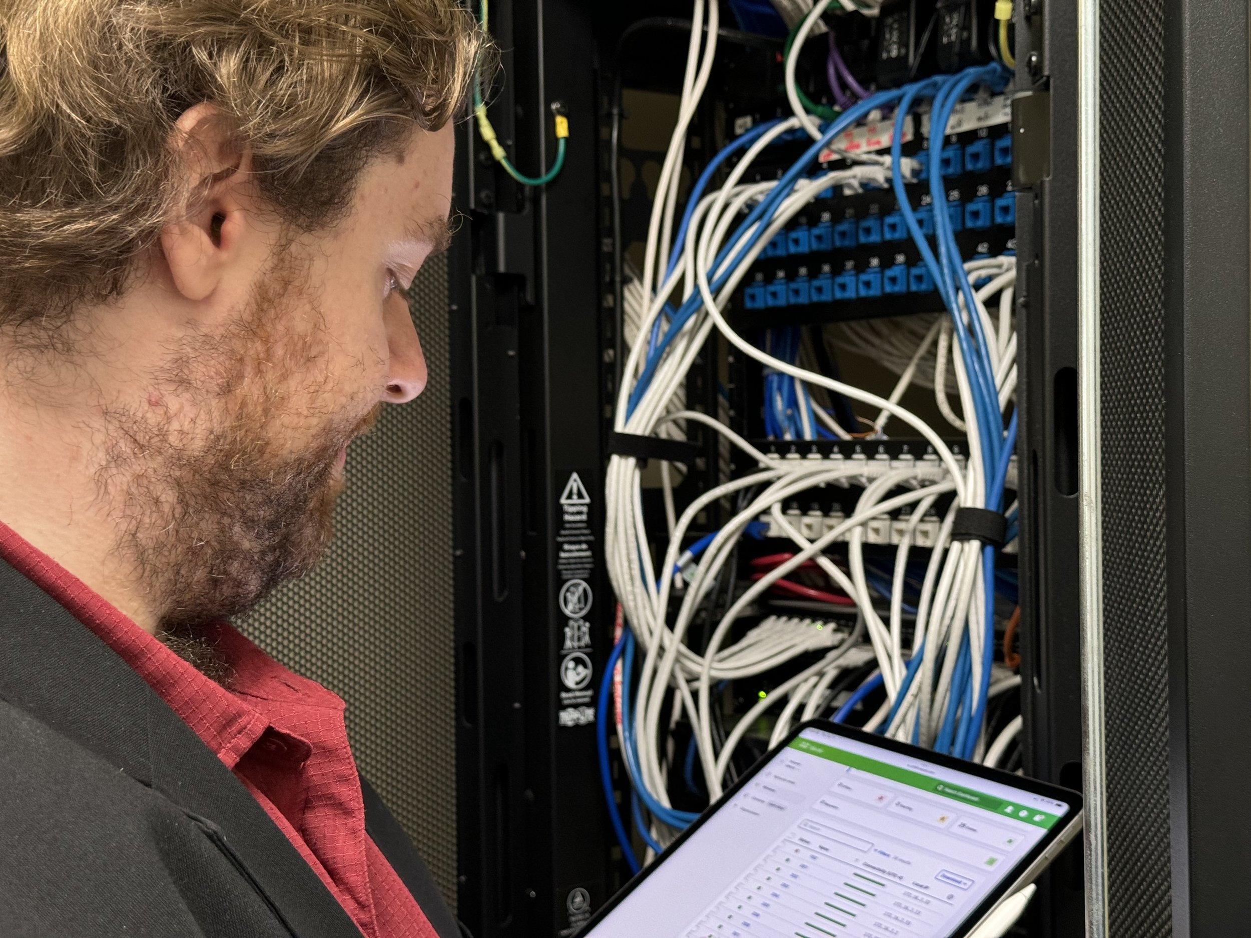  Alex monitors network performance from an iPad Pro while standing in a server closet. 