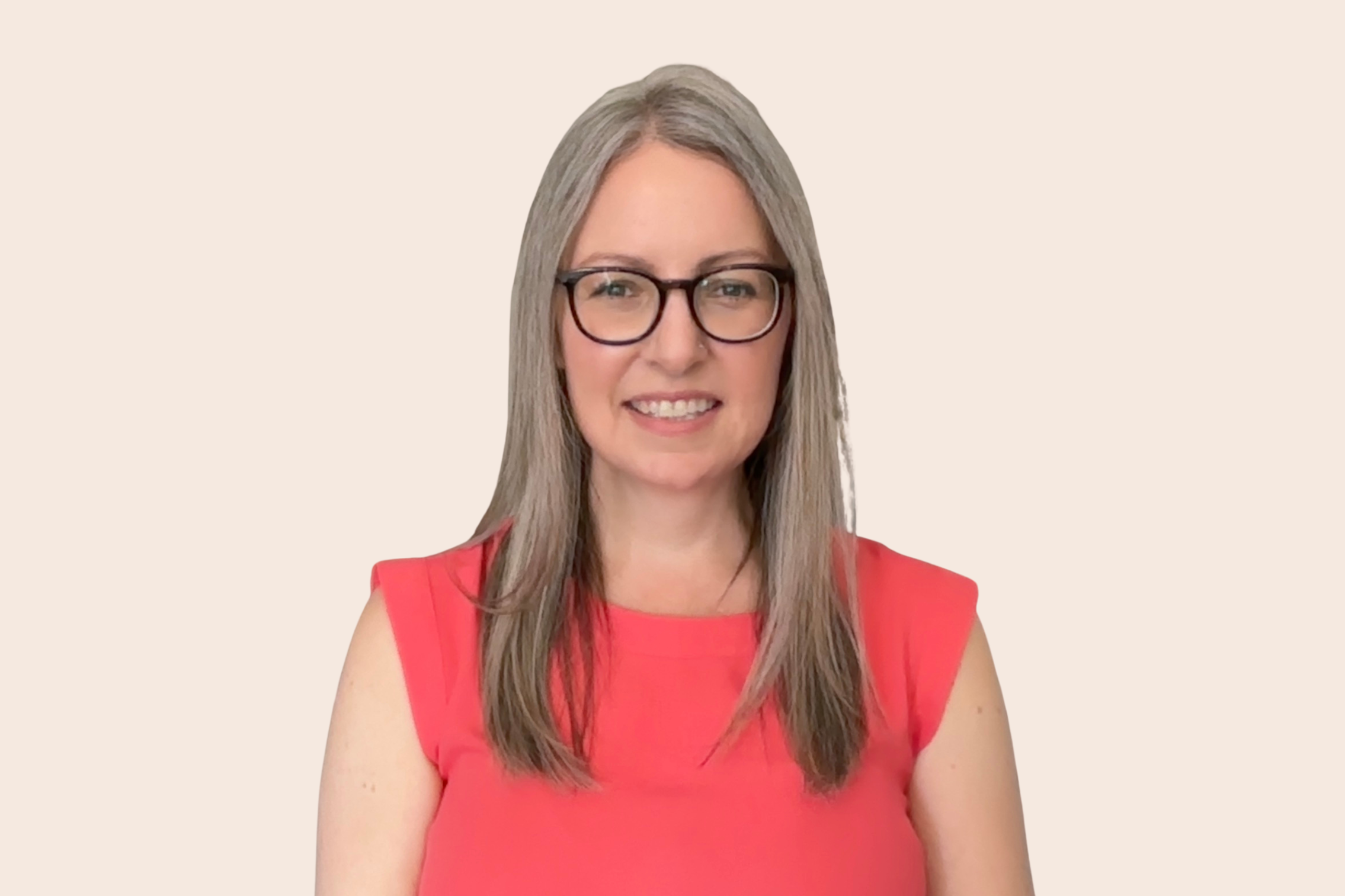 A woman with long gray hair, glasses, and a red sleeveless dress smiling at the camera against a plain beige background.
