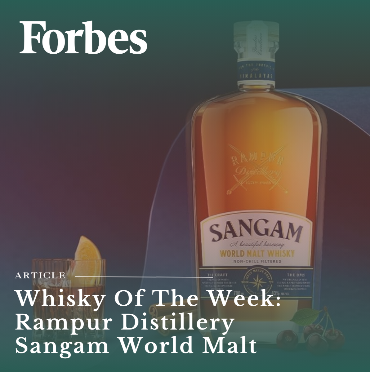 A bottle of Sangam World Malt Whisky with a glass containing a lemon wedge and cherries in front of it.
