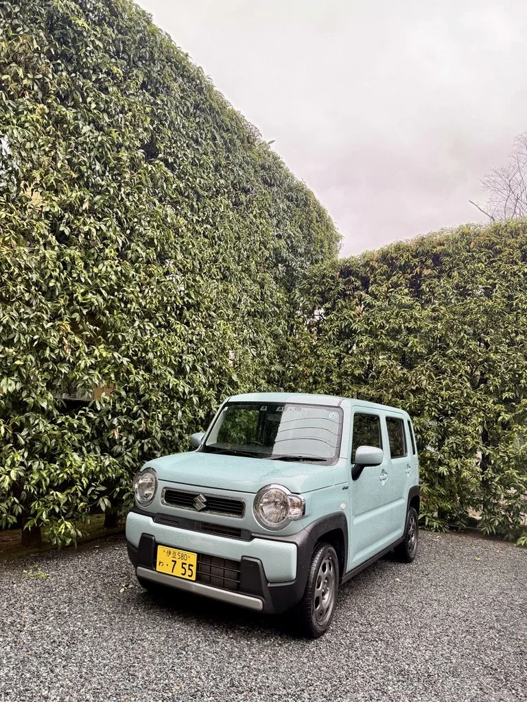 Light blue Kei car with a yellow license plate.