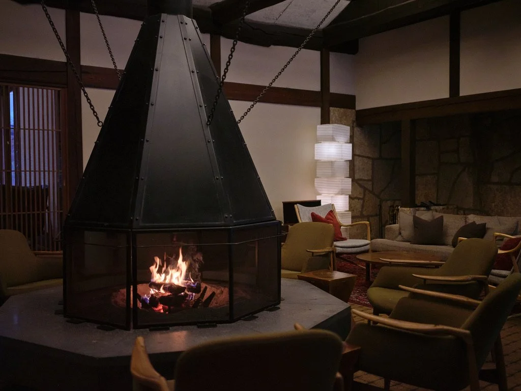 Lounge with a suspended metal fireplace and chairs arranged around it.