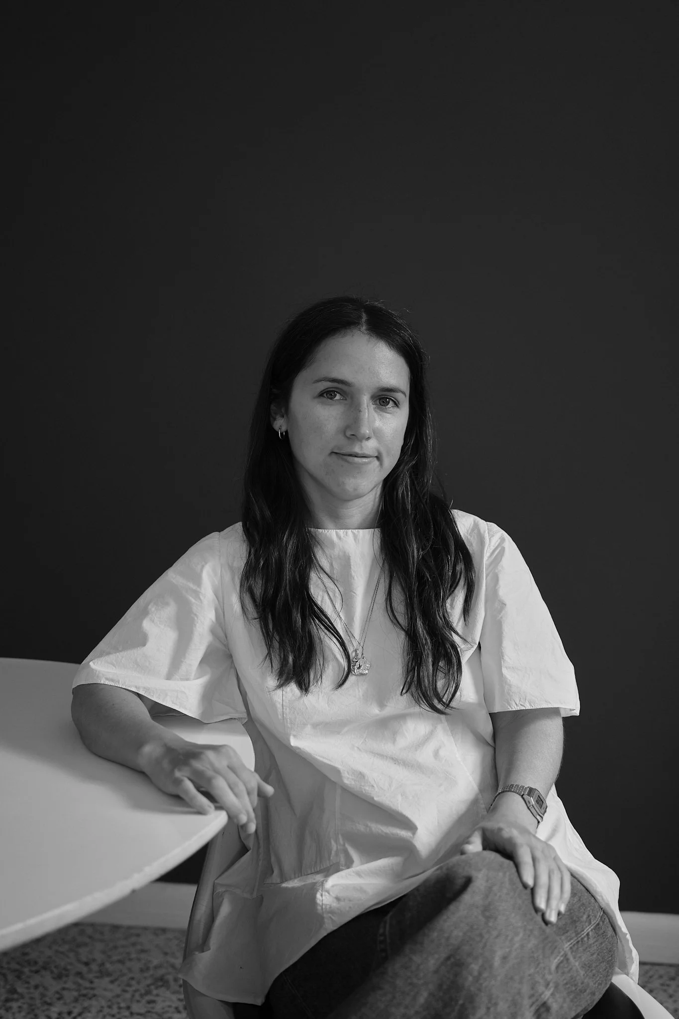 Portrait of Sophia Hatchitt seated beside a round table in a minimalist room.