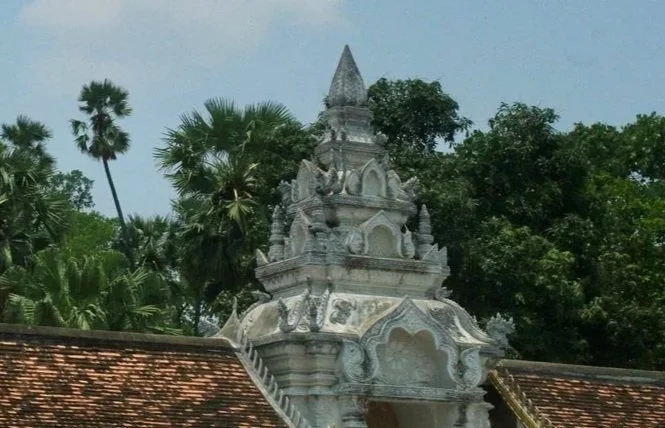 Temple structure with carved details, a tiled roof, and trees surrounding it.