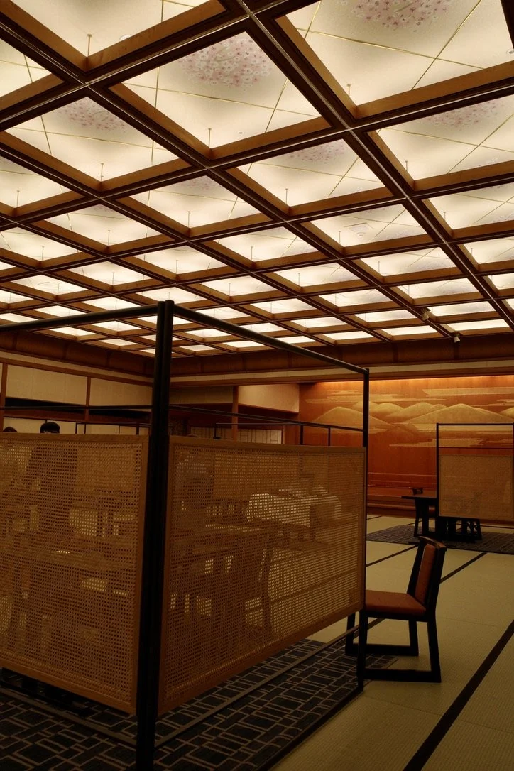 Room with illuminated ceiling panels, wooden partitions, and arranged seating.