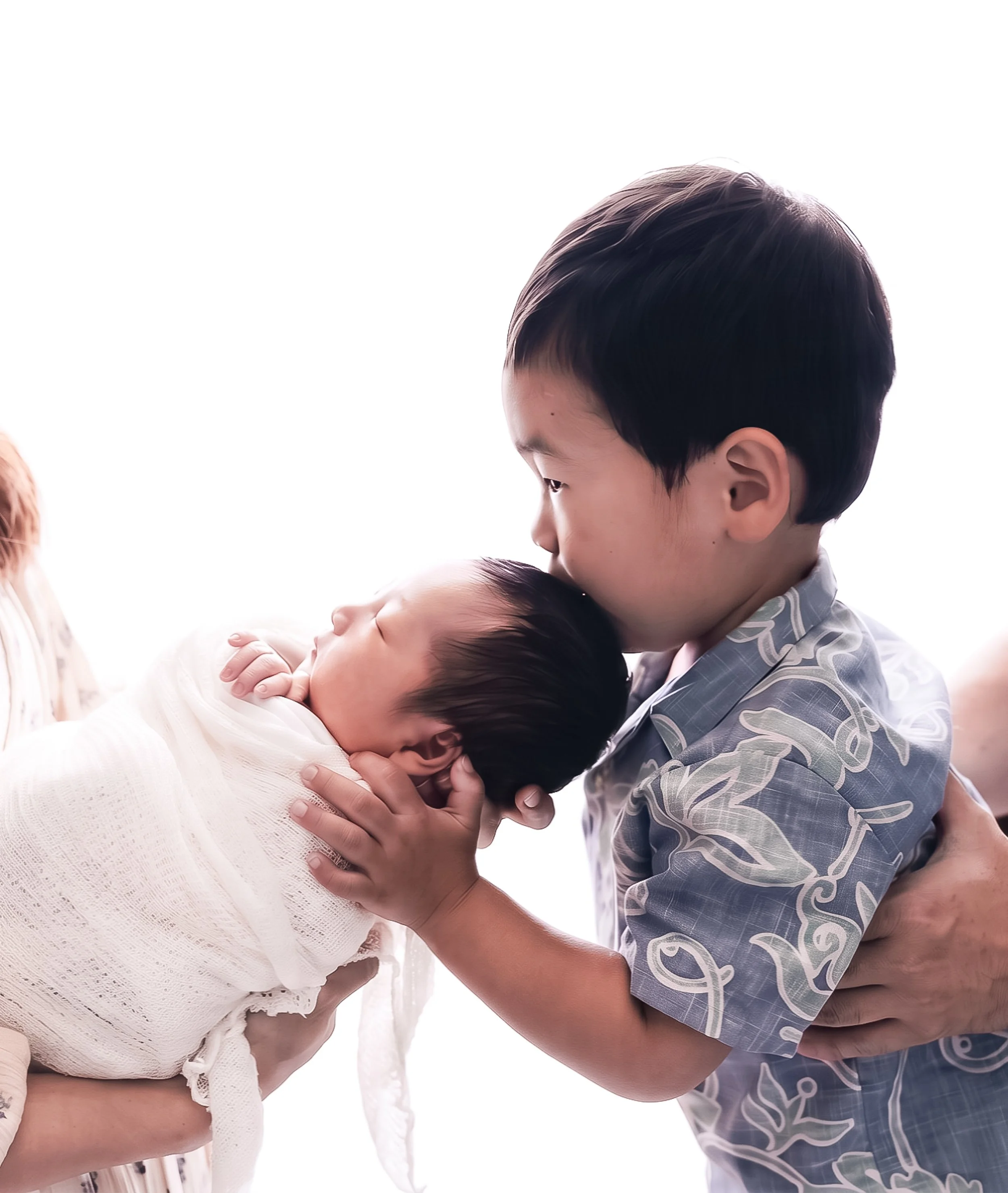 A young boy holding a newborn baby, both of them showing affection and intimacy.