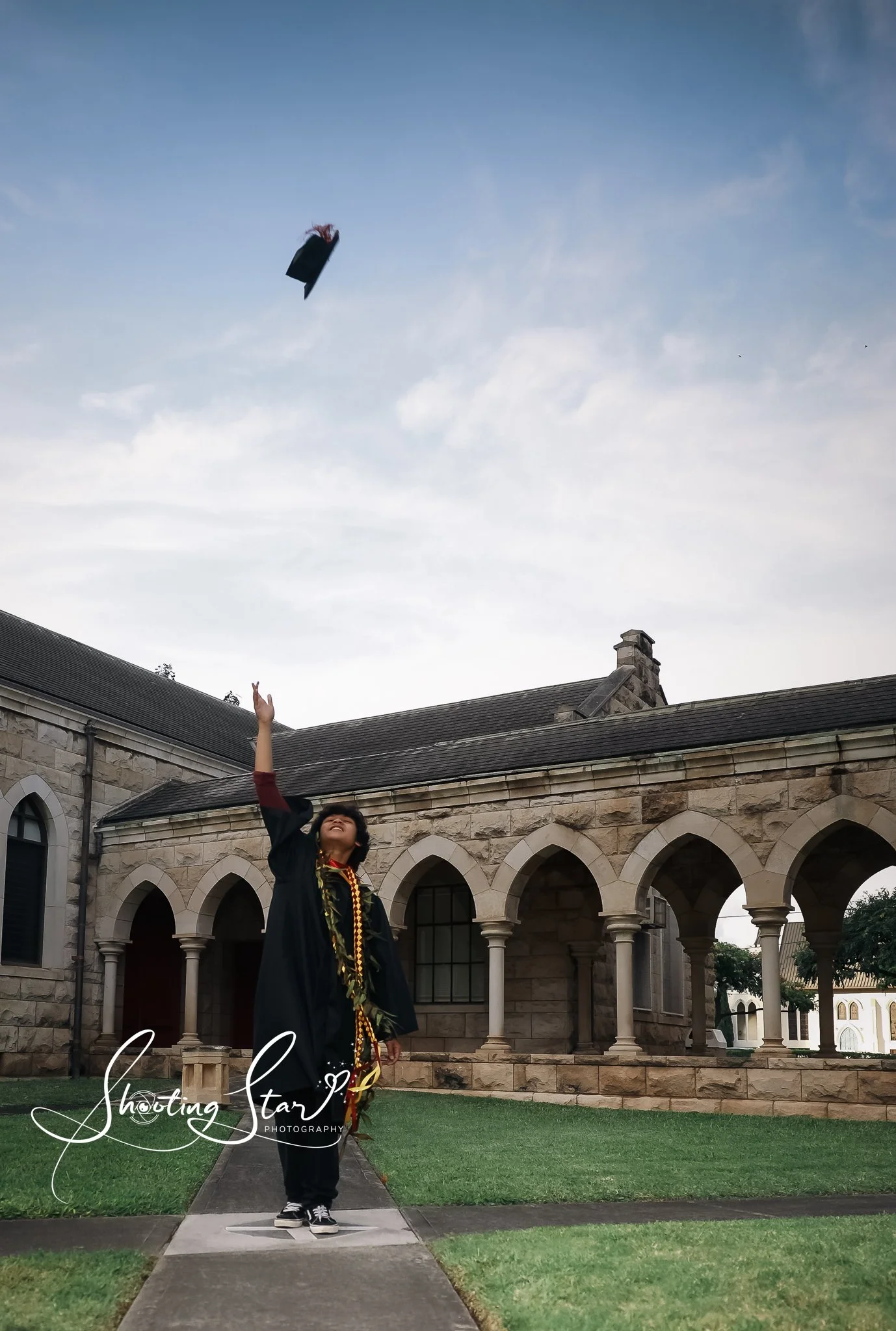 Graduation gown and cap throwing their cap into the sky pose