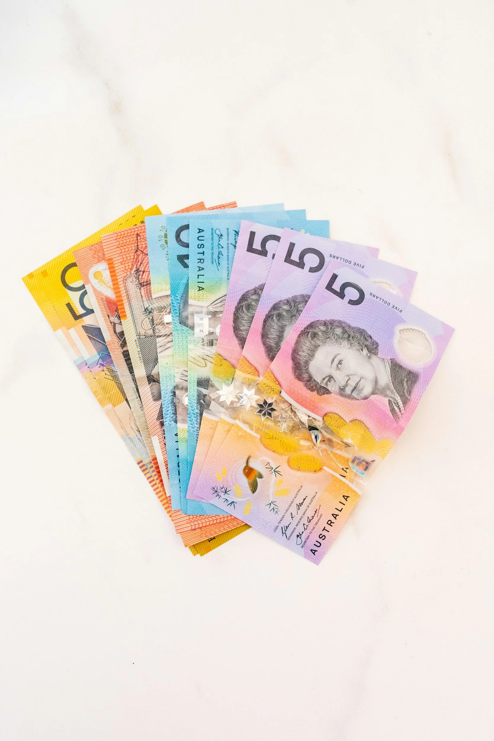 Australian currency bills in various denominations fanned out on a white surface.