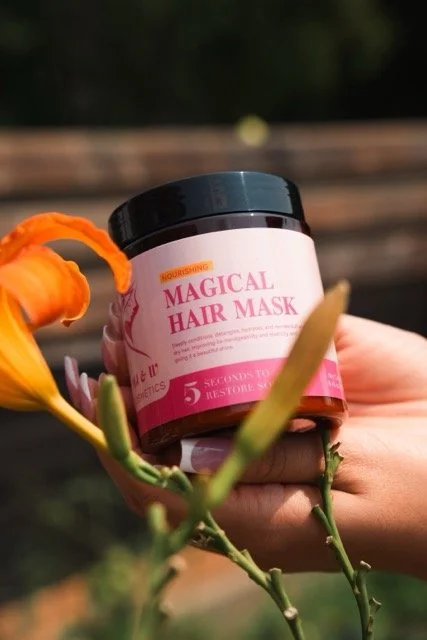 Magical hair mask by MJ&W Cosmetics held in hand in a beautiful flower setting. Hair mask made for dry hair and broken ends. 