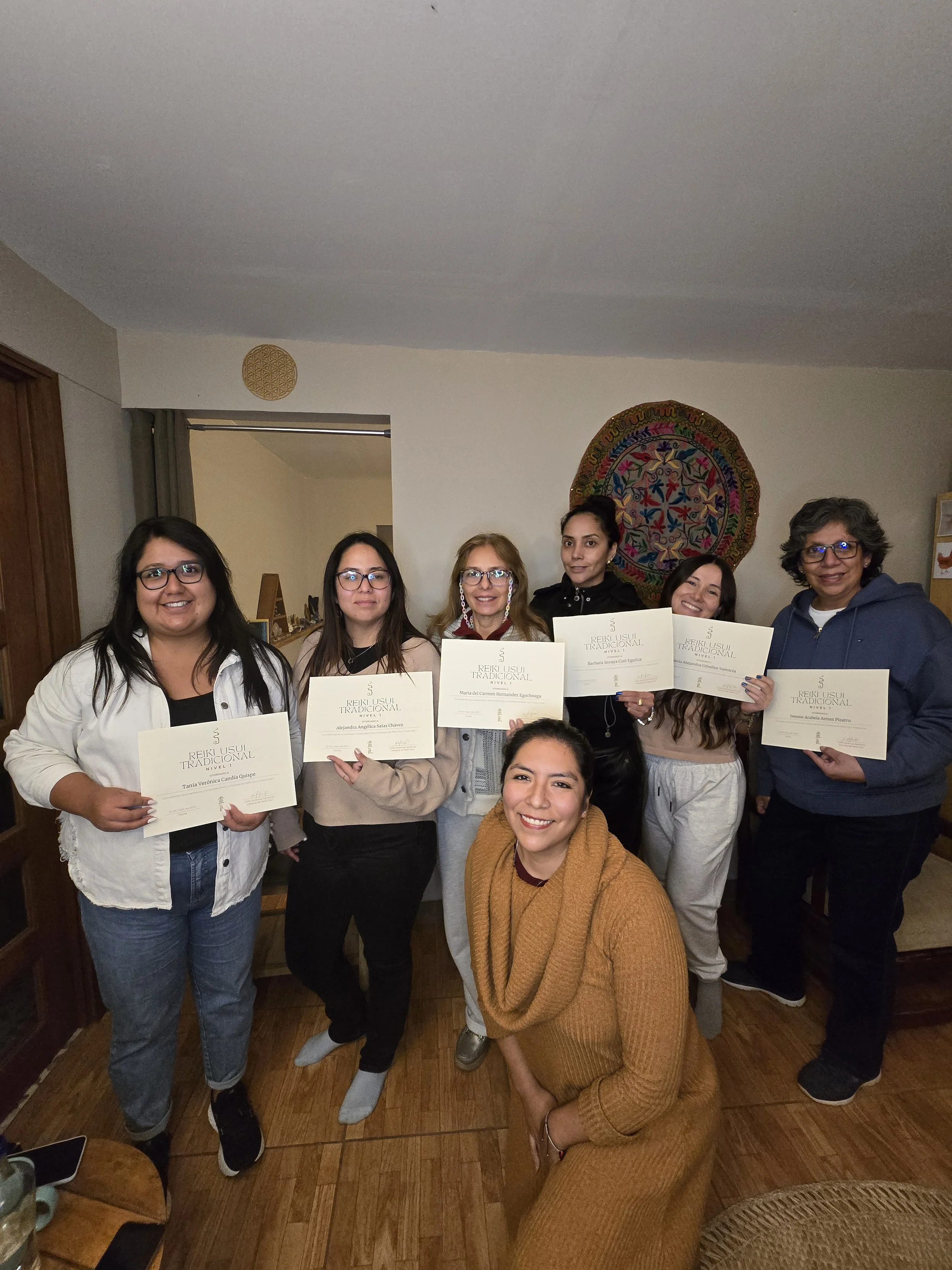 A group of eight diverse women, holding certificates of their Reiki training.