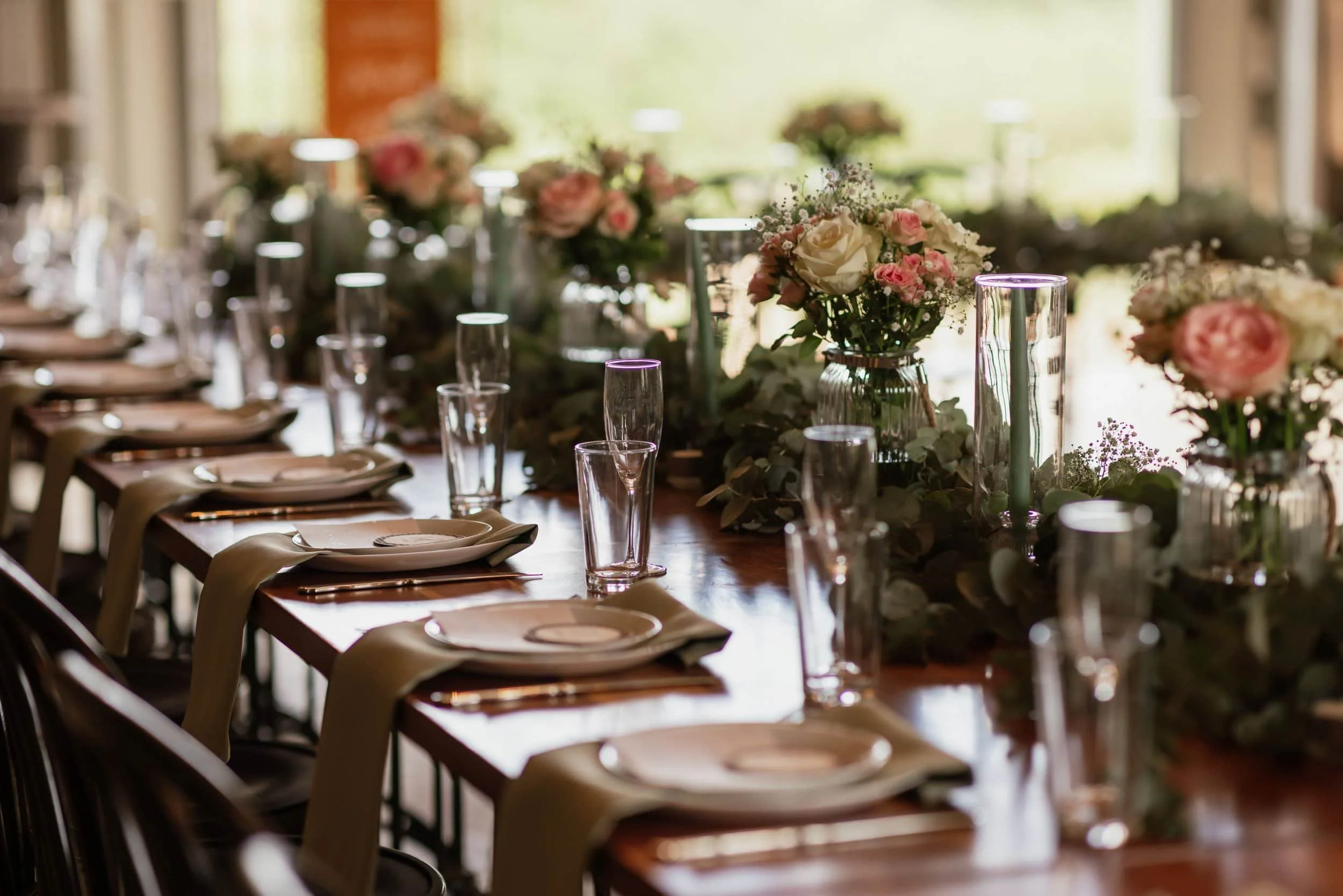 A reception table decorated with flowers and glassware, set for a formal event or gathering.