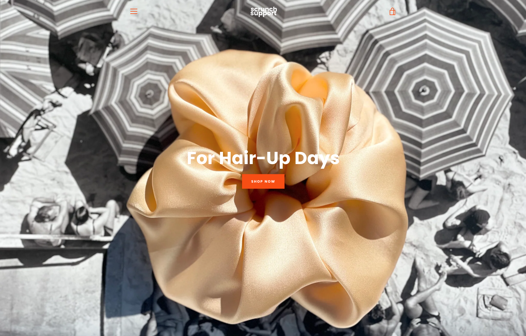 Close-up of a silky scrunchie on a black-and-white beach background with striped umbrellas and sunbathers, featuring text "For Hair-Up Days."