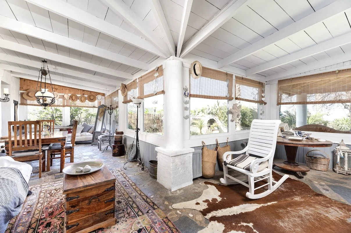 Offener Wohnbereich mit Schaukelstuhl und weiß getünchten Balken in der Villa Paradiso Kos, Griechenland