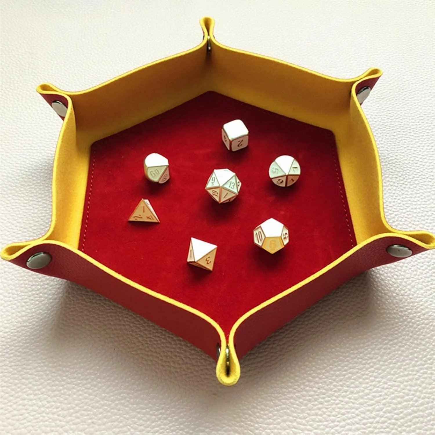 A collection of multi-sided dice tray in a red and yellow leather tray with a red felt interior, used for tabletop role-playing games.