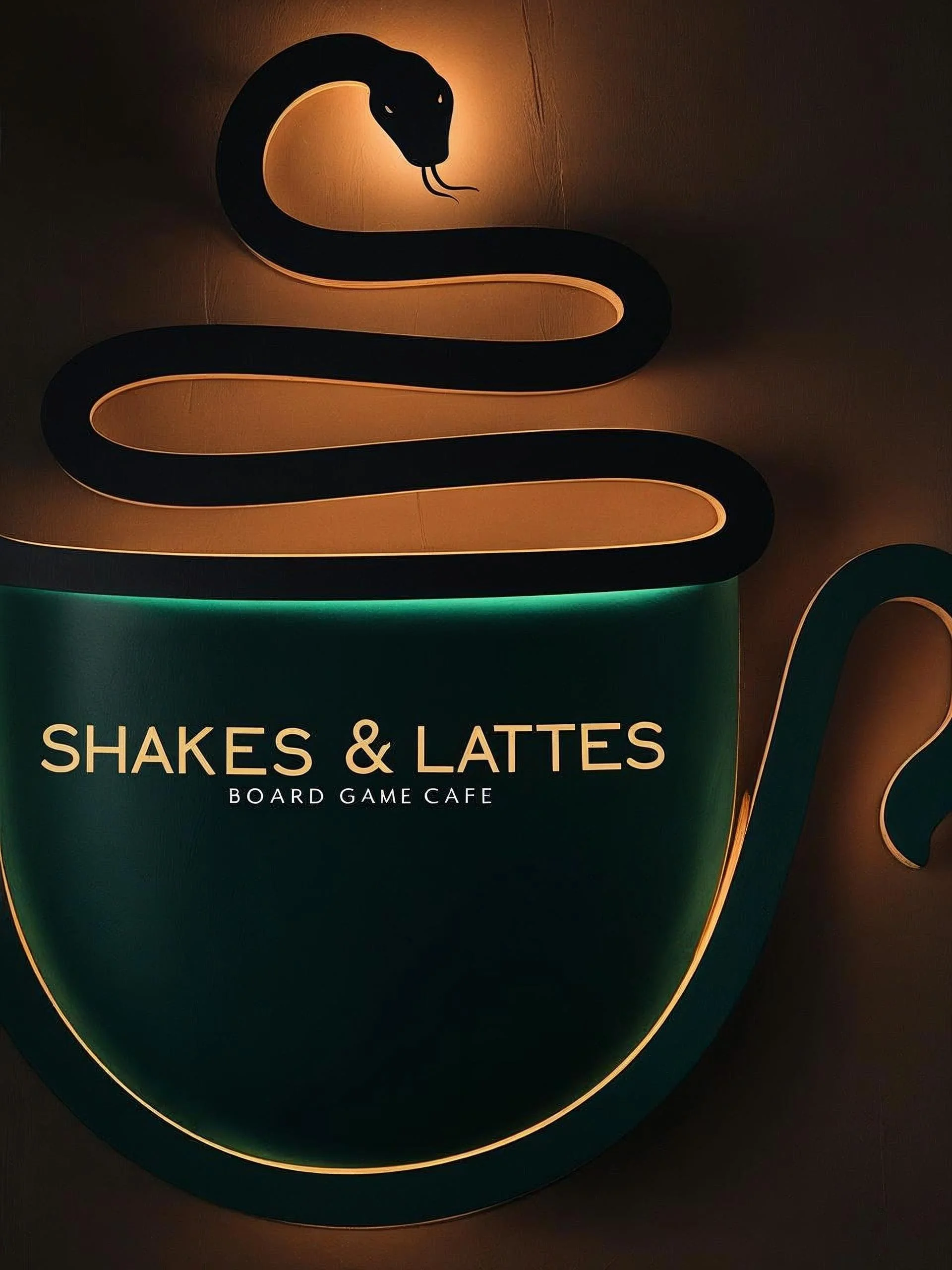 Illuminated sign of a black snake forming a coffee cup, with the text 'SHAKES & LATTES' and 'BOARD GAME CAFE' underneath.
