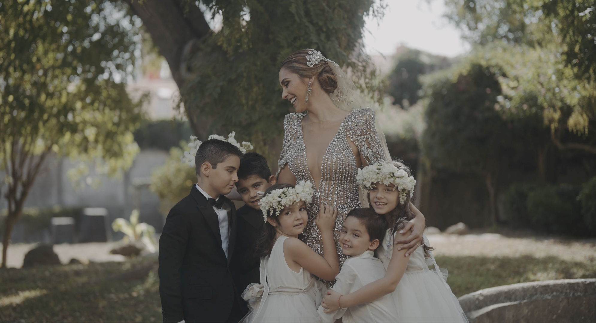 Candid moment with bride in Elie Saab gown and flower children in a palace garden. Emotional destination wedding cinematography in Portugal by Maru Films.