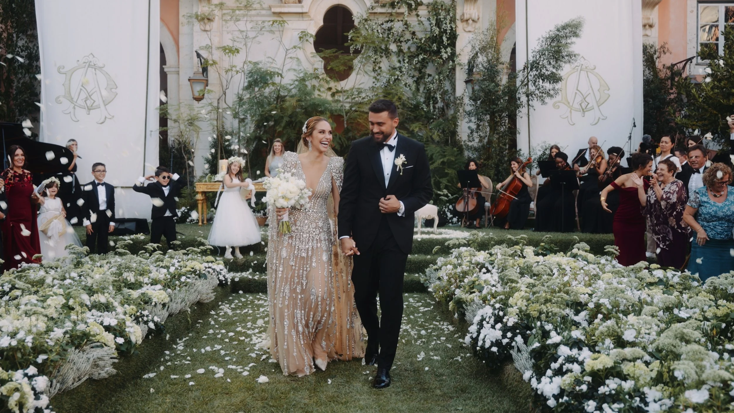 Bride and groom walking through a live orchestra at Palácio do Correio-Mor. High-end wedding cinematography in Portugal by Maru Films.