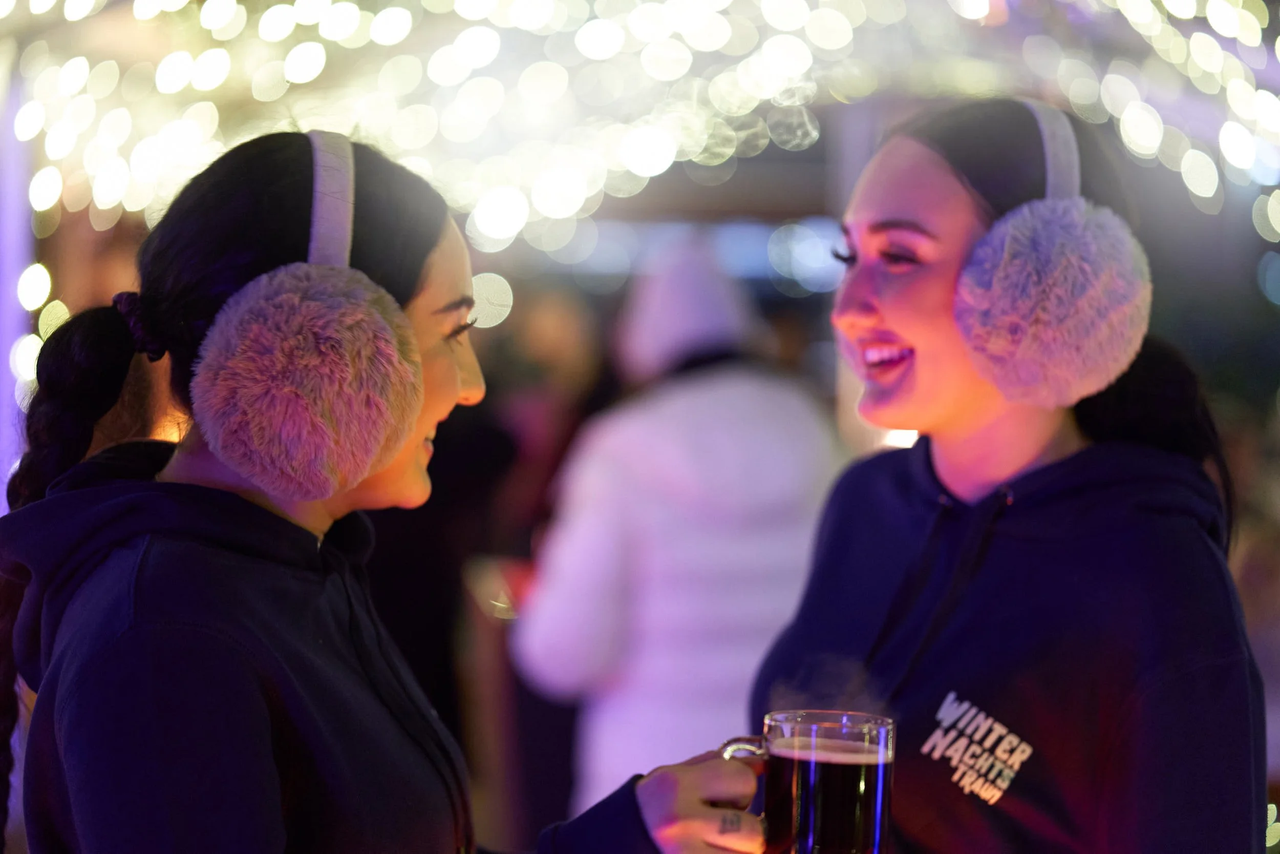 Zwei lächelnde Frauen mit Ohrenfellkopfhöhrern.
