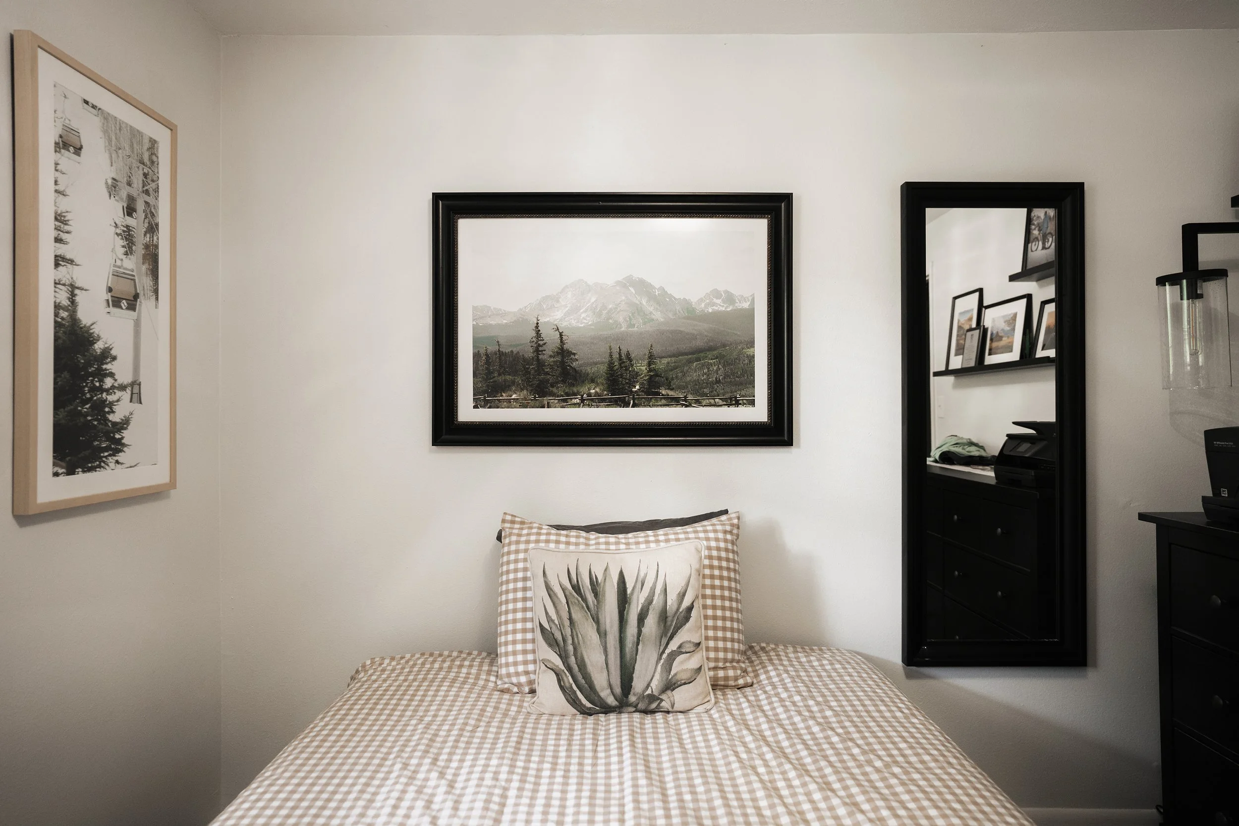 Framed western landscape print displayed above a bed in a bedroom.