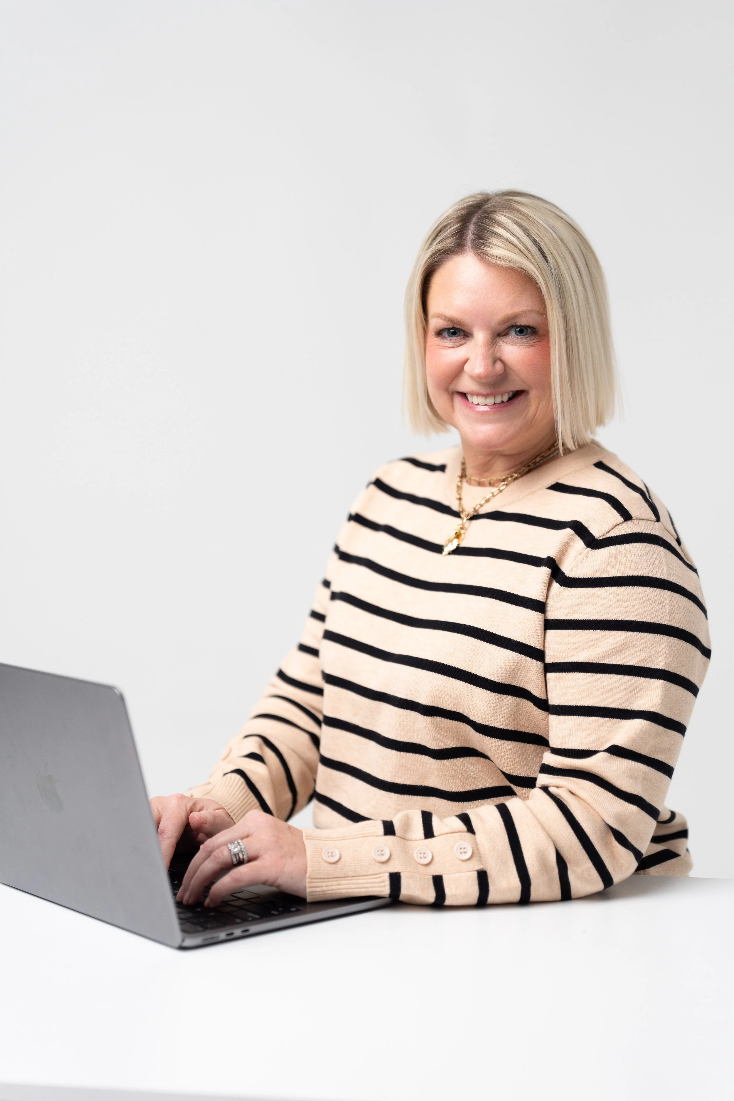 Jennings King in striped sweater using a laptop at a white desk