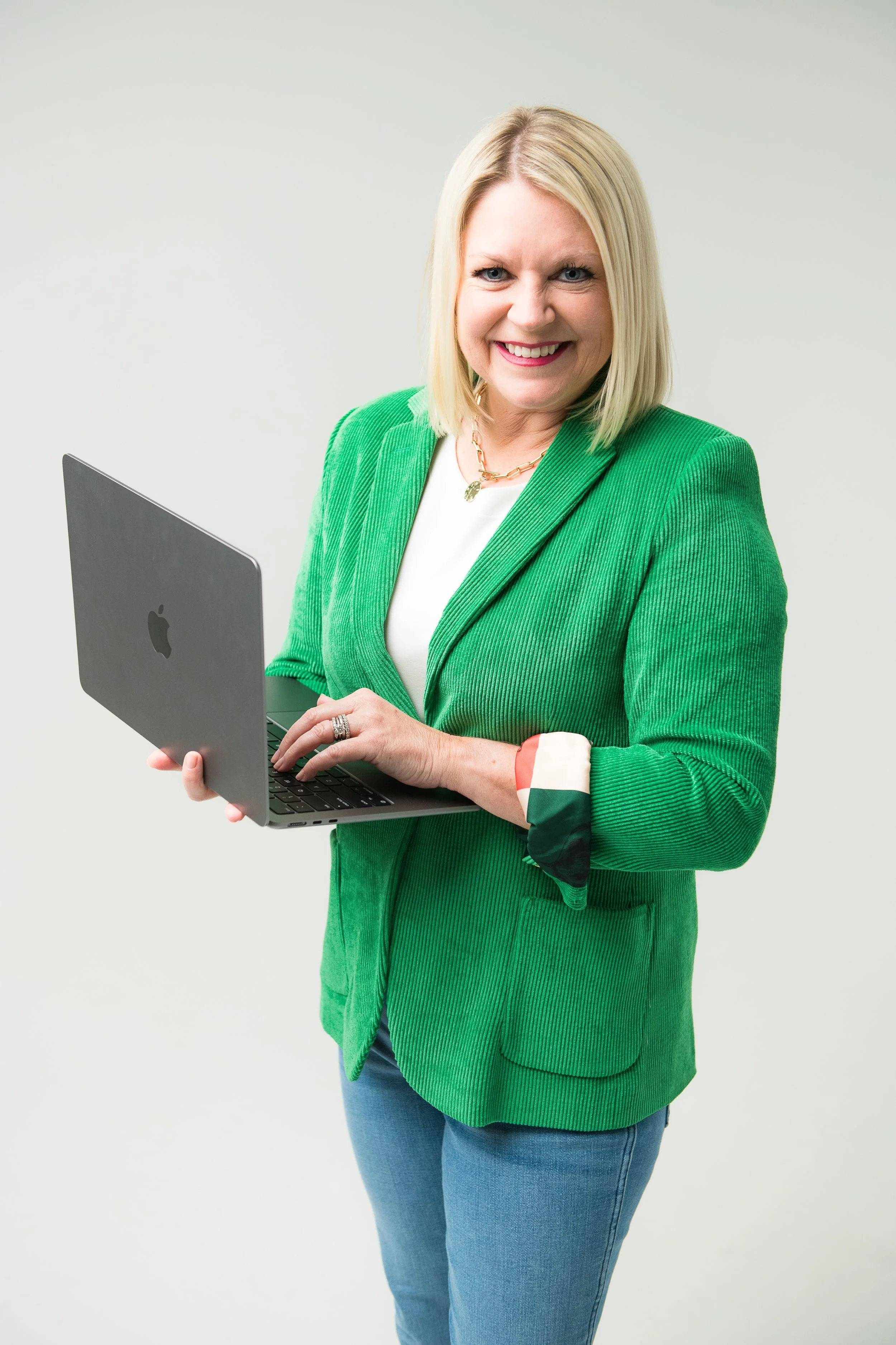 Jennings King in green blazer holding a laptop and smiling