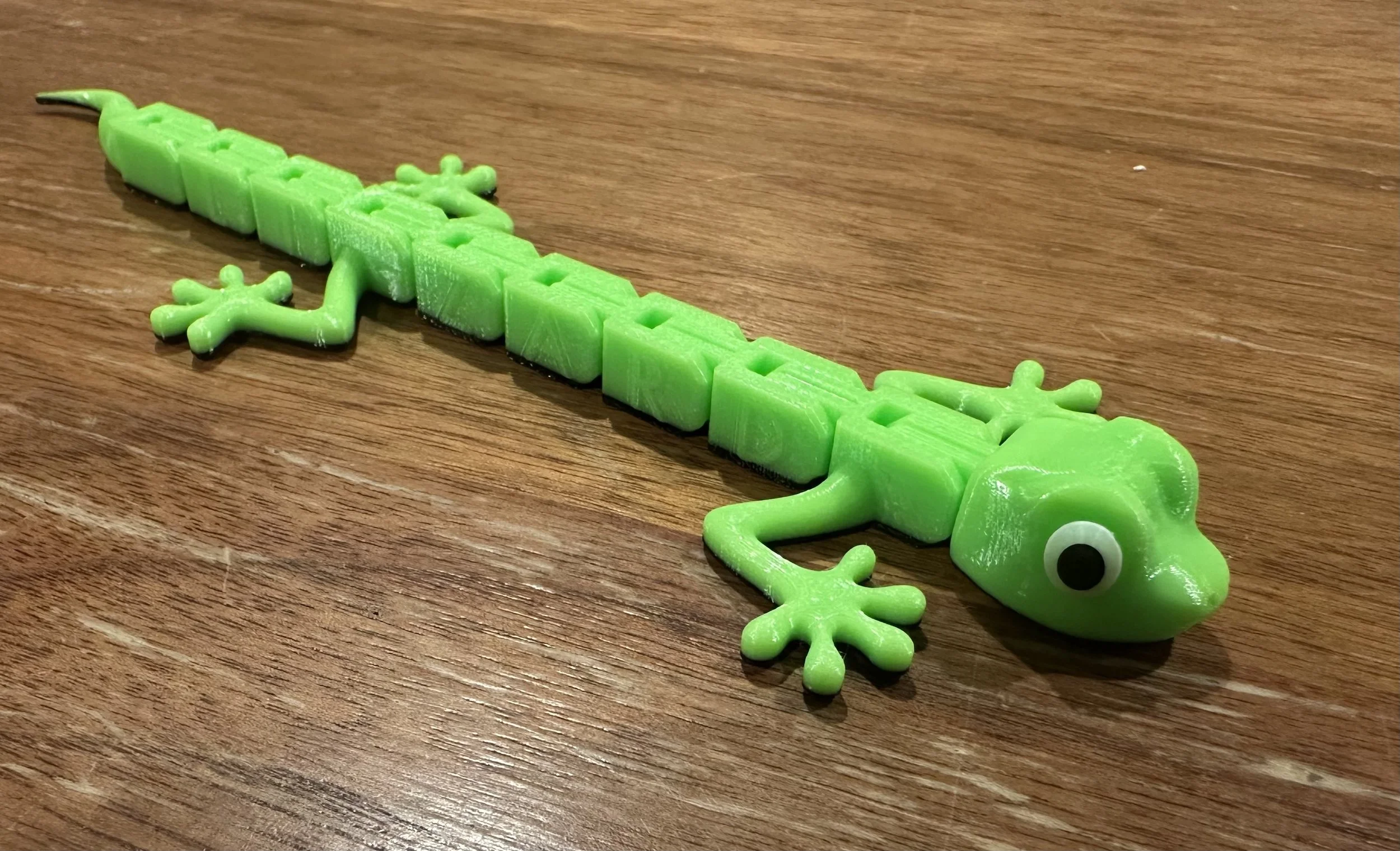 Green lizard stretched out on a wooden table.