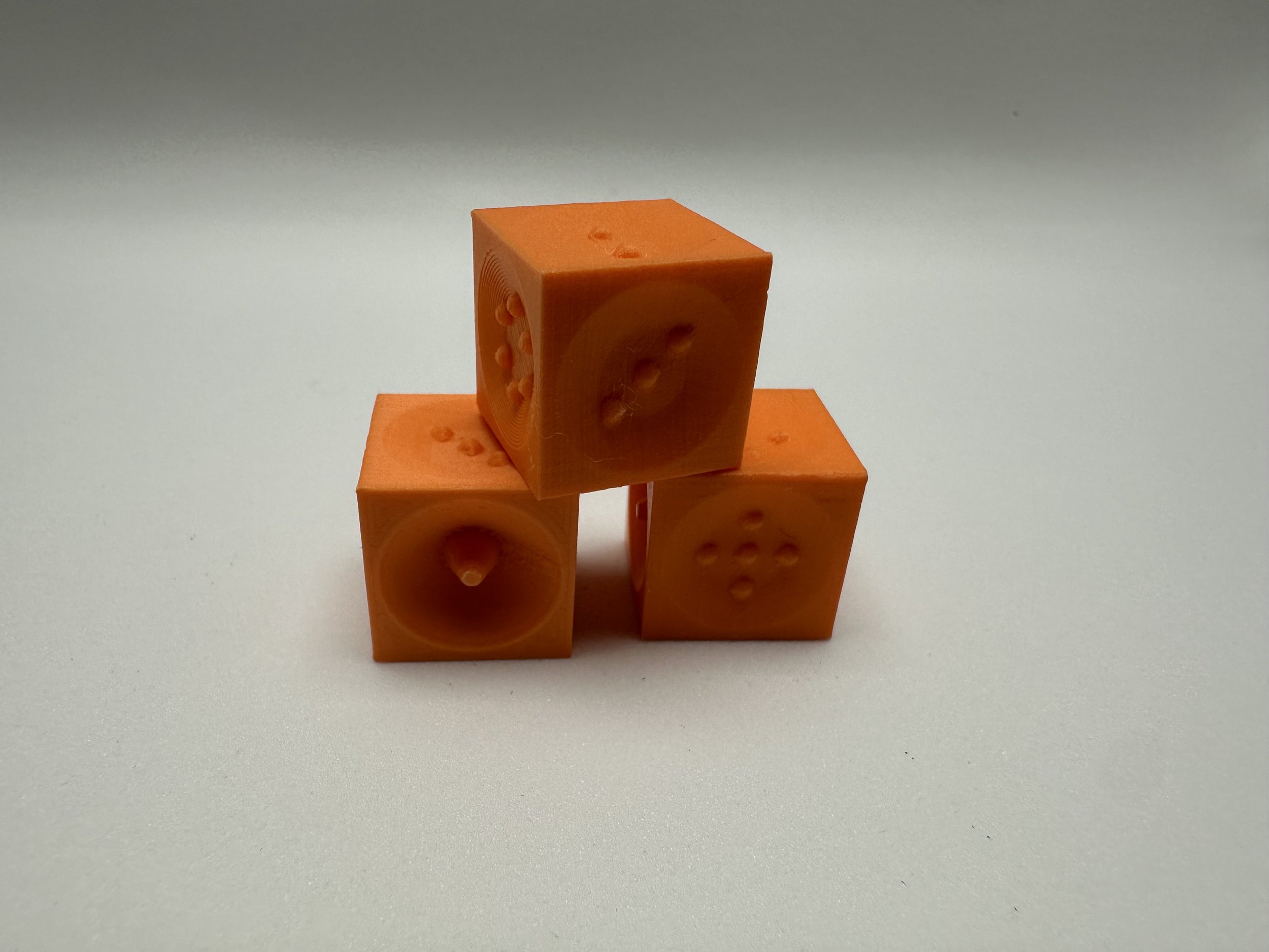 3 Orange dice with pointed corners stacked in a pyramid, sides 1, 3, and 5 face outward.