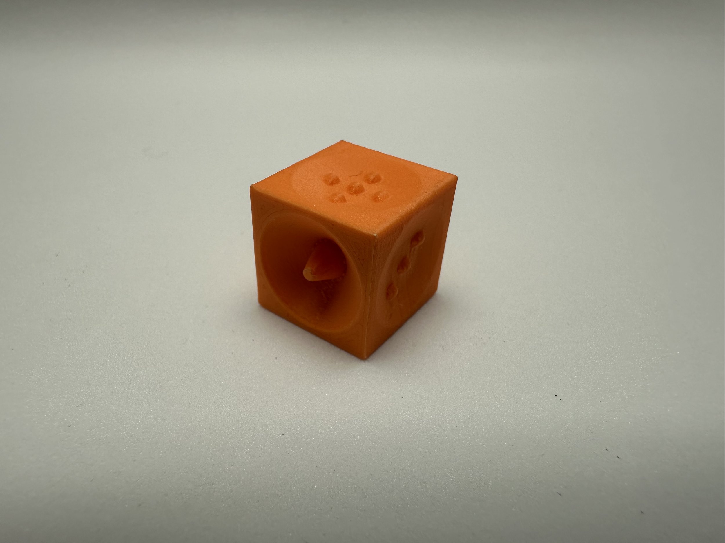 1 Orange die with pointed corners, sides 6, 4, and 1 face outward.