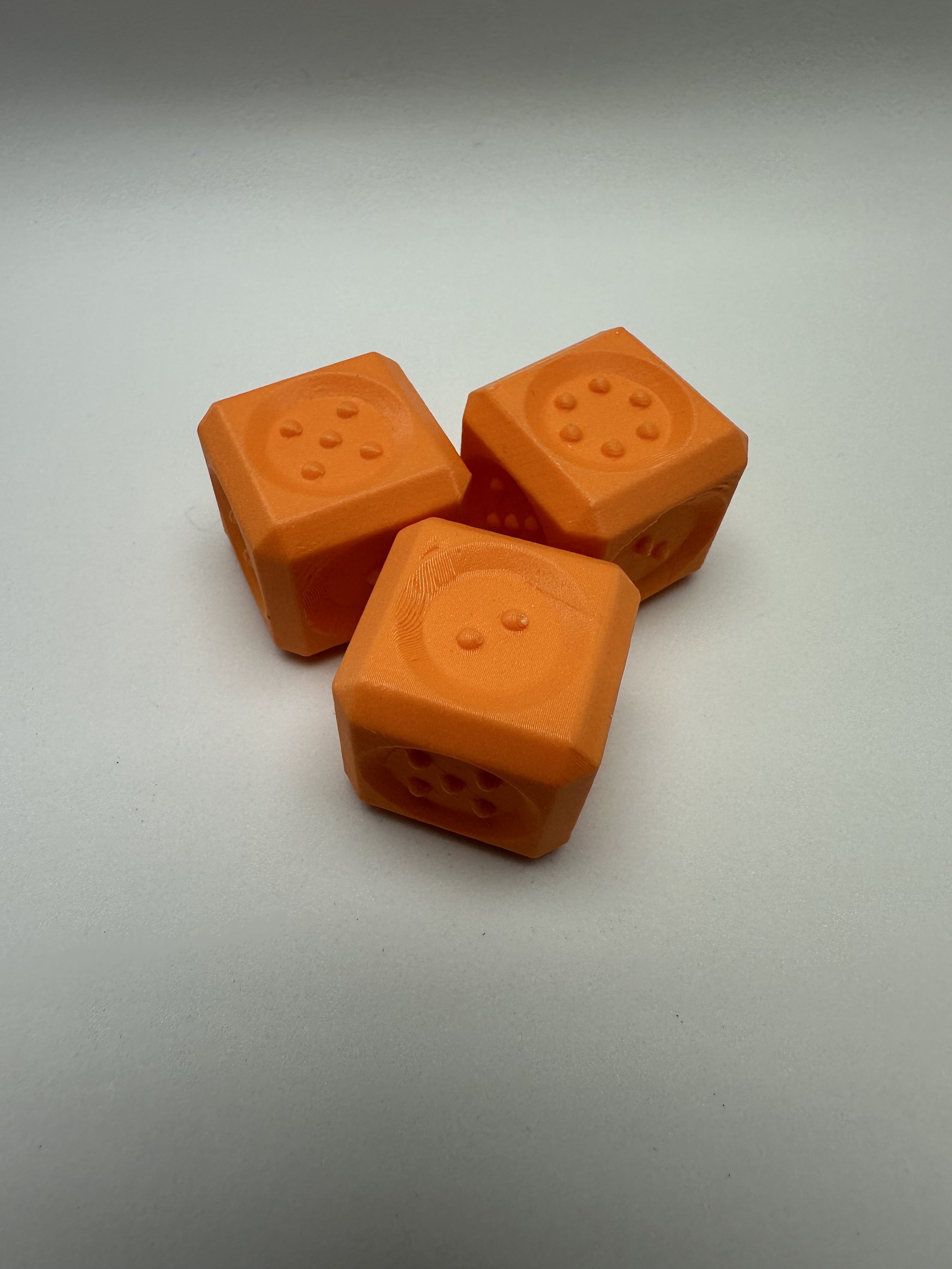 3 Large, orange dice with rounded edges, sides 5, 6, and 2 face upward.