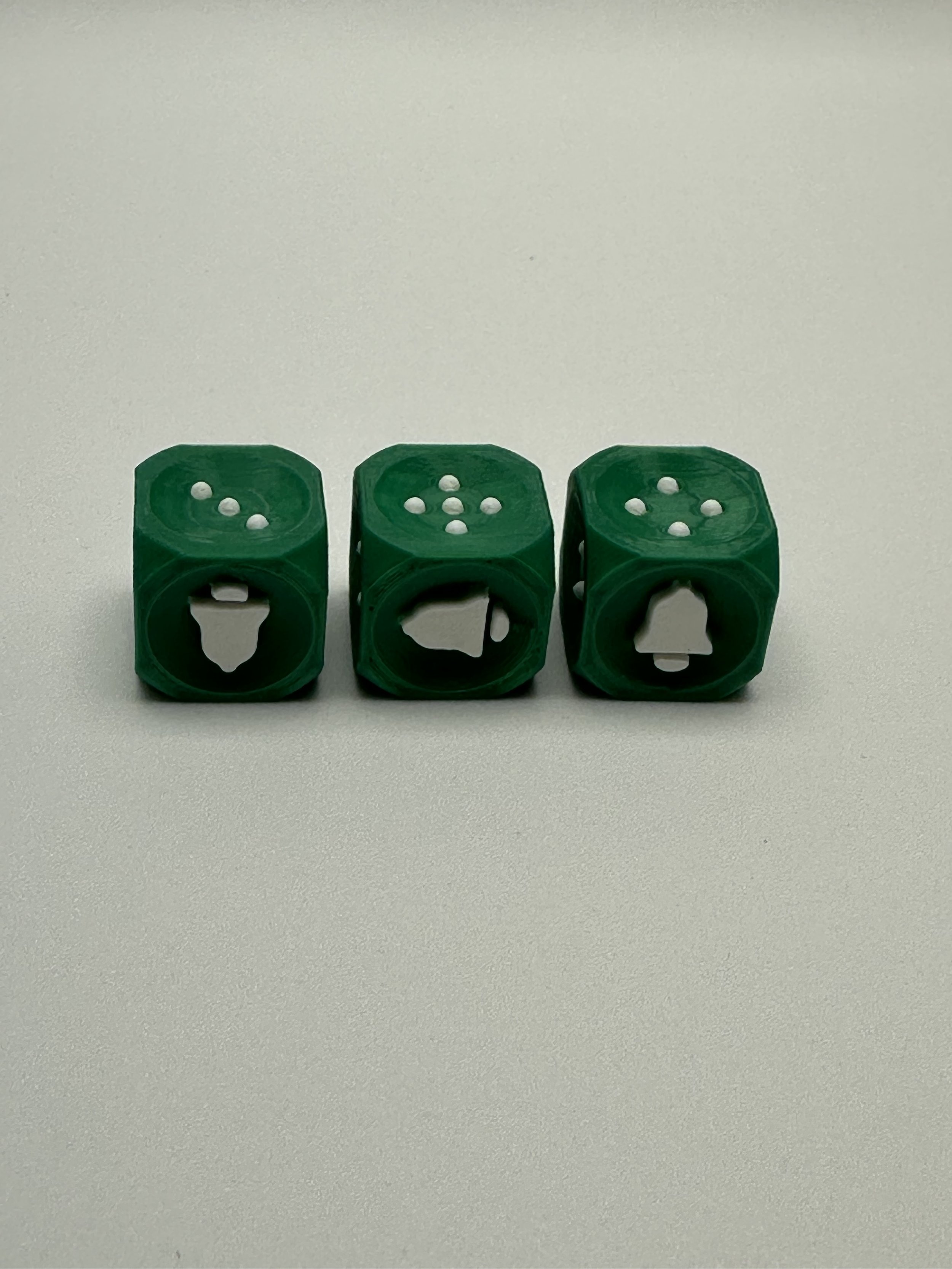 3 green bell dice feature white bells on the front and white pips on the top.