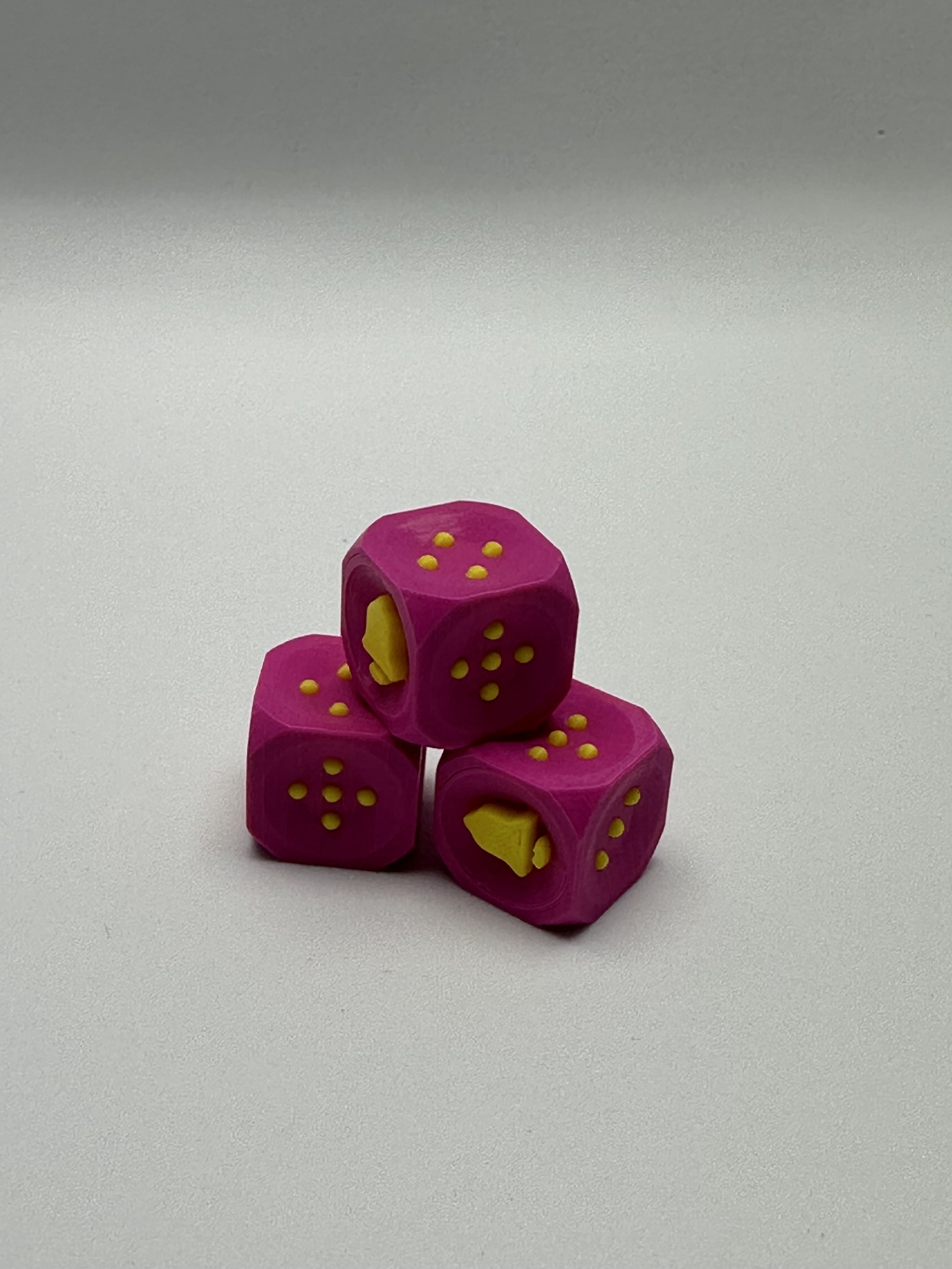 3 pink and sunshine yellow bell D6 stacked in a pyramid against a white background, showing sides 4, 5, and 6 (bell).