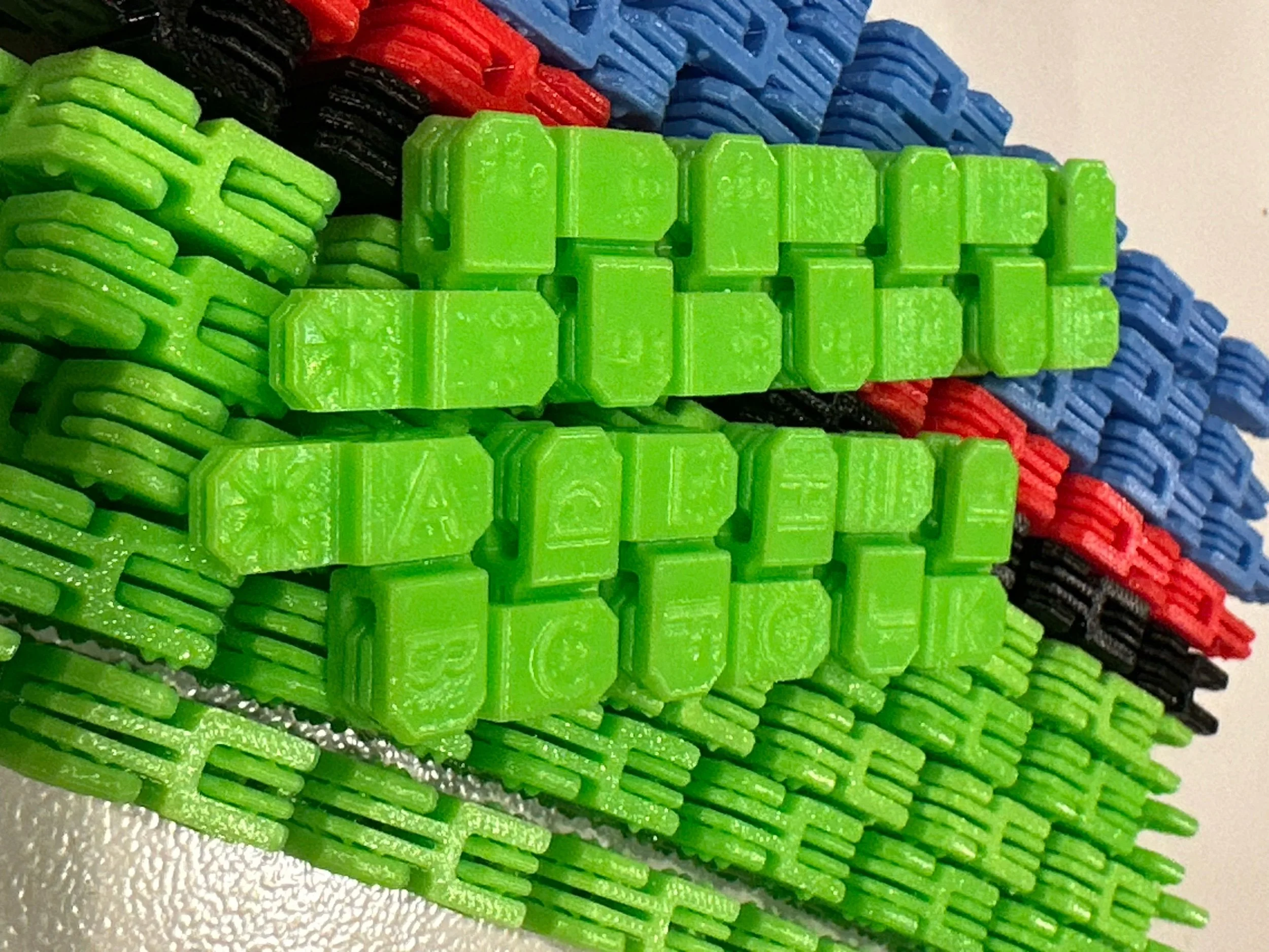 Lime green fidget showing print side, resting on top of a bundle of other fidgets.