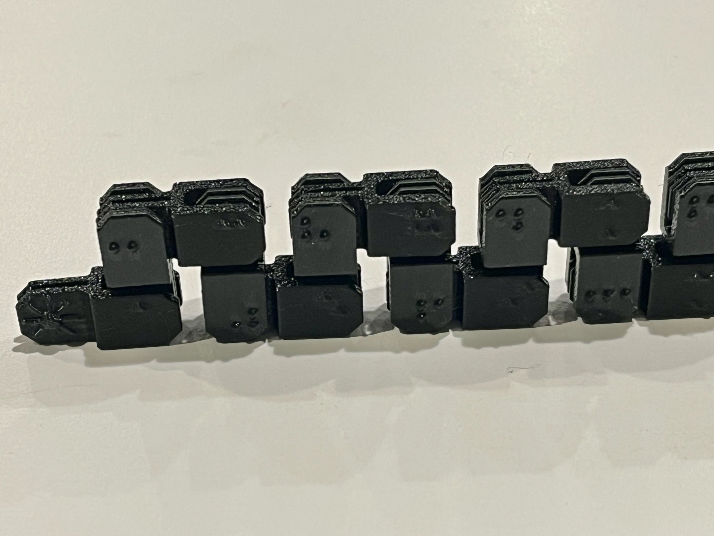 Black fidget in a long accordion fold, braille side facing outward.