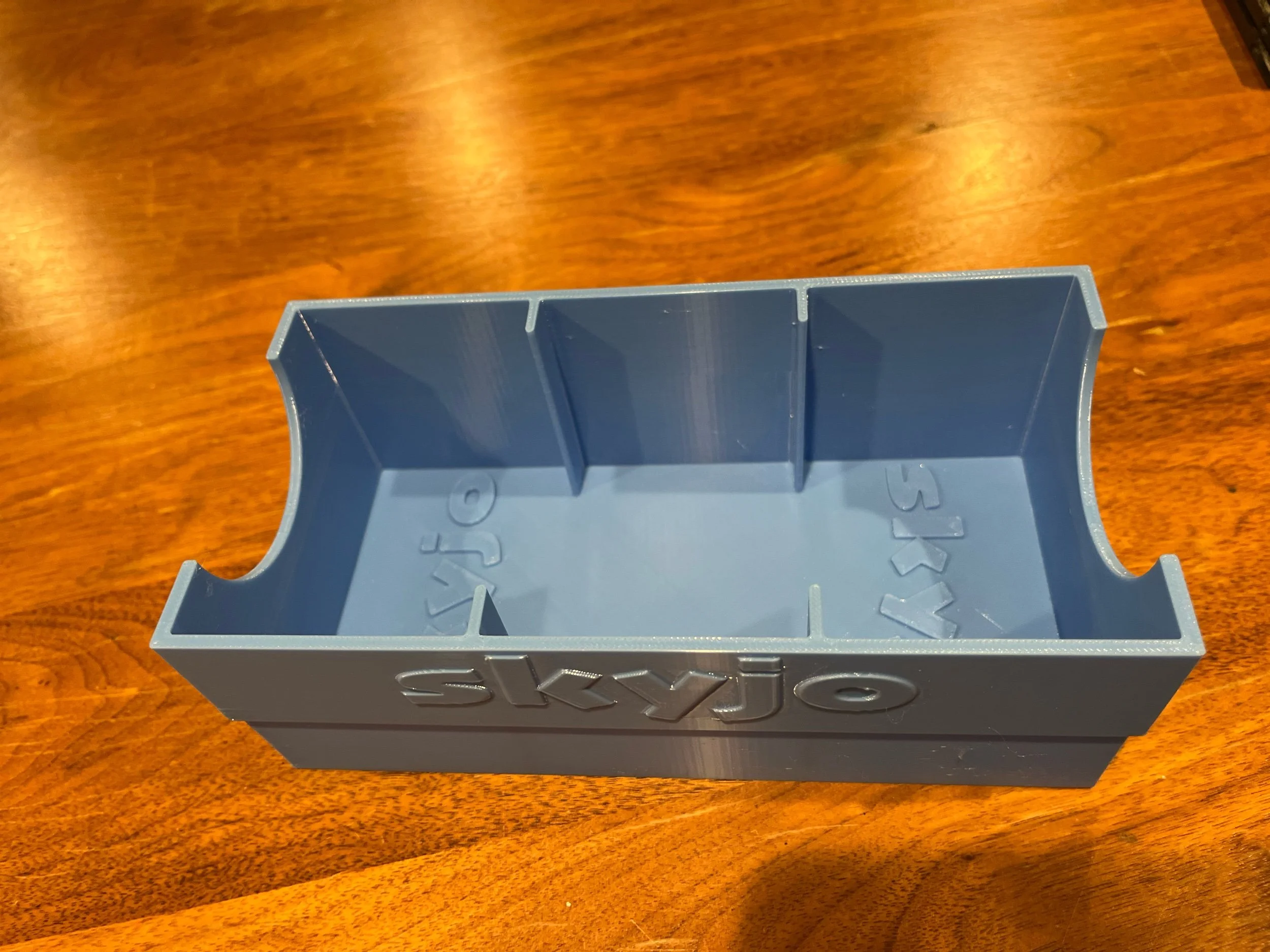 Blue SKYJO insert shown empty, against a wooden surface.