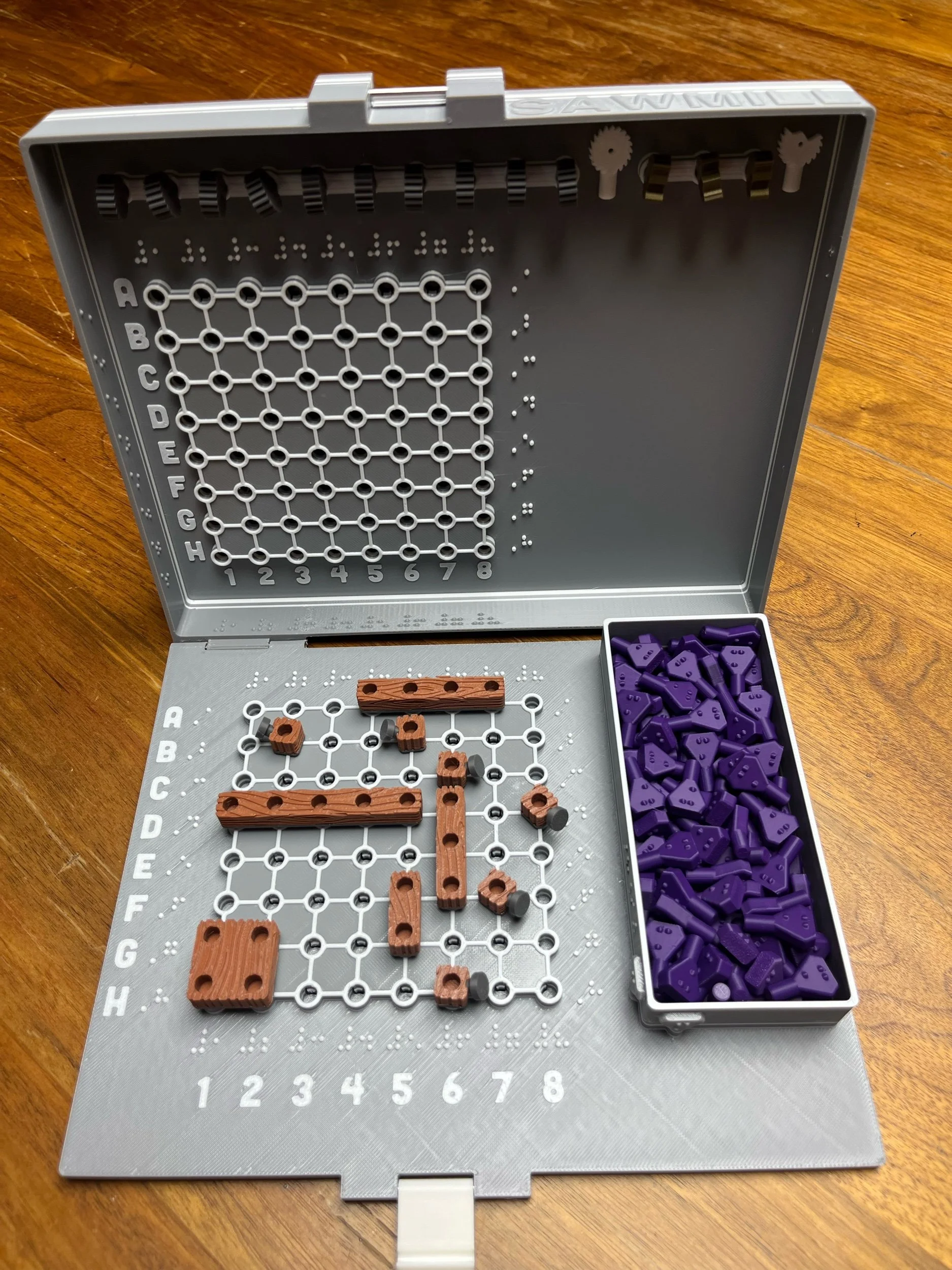 Open game case with grids located inside both the top and bottom sections. Saws are stored inside the top, and markers and boards stored inside the base.