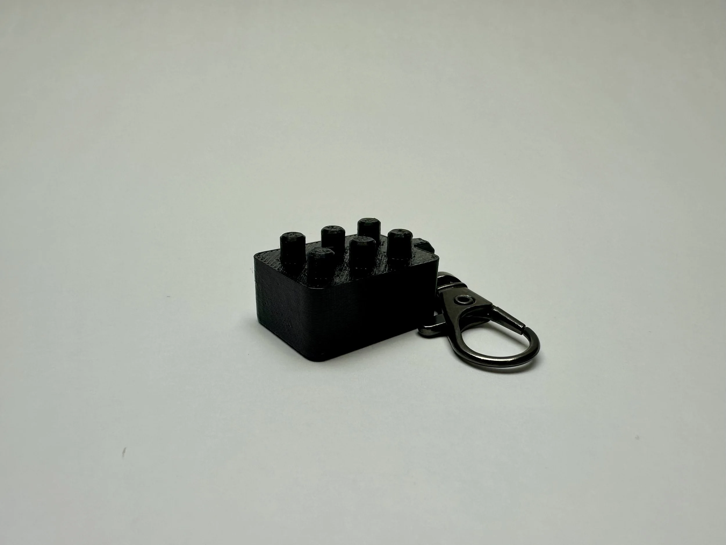 Black braille cell fidget, with all 6 black pegs up.