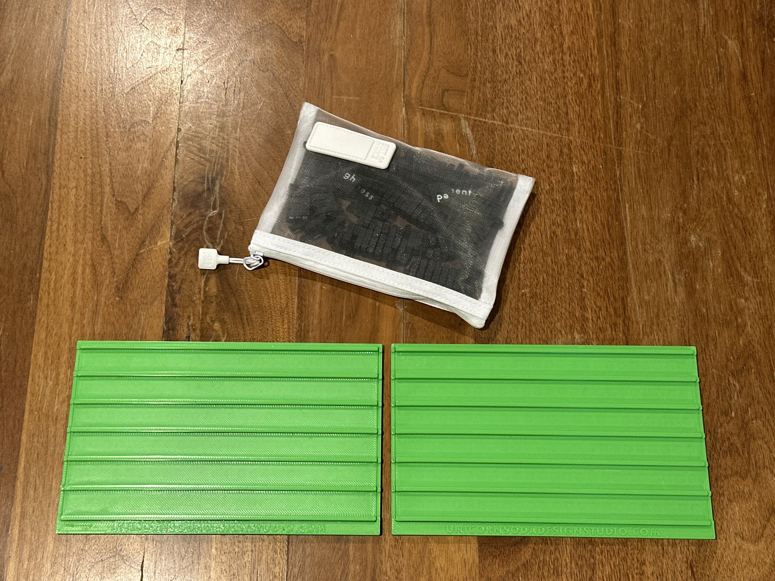 2 green slide literacy boards and one mesh bag of black tiles atop a wooden table.