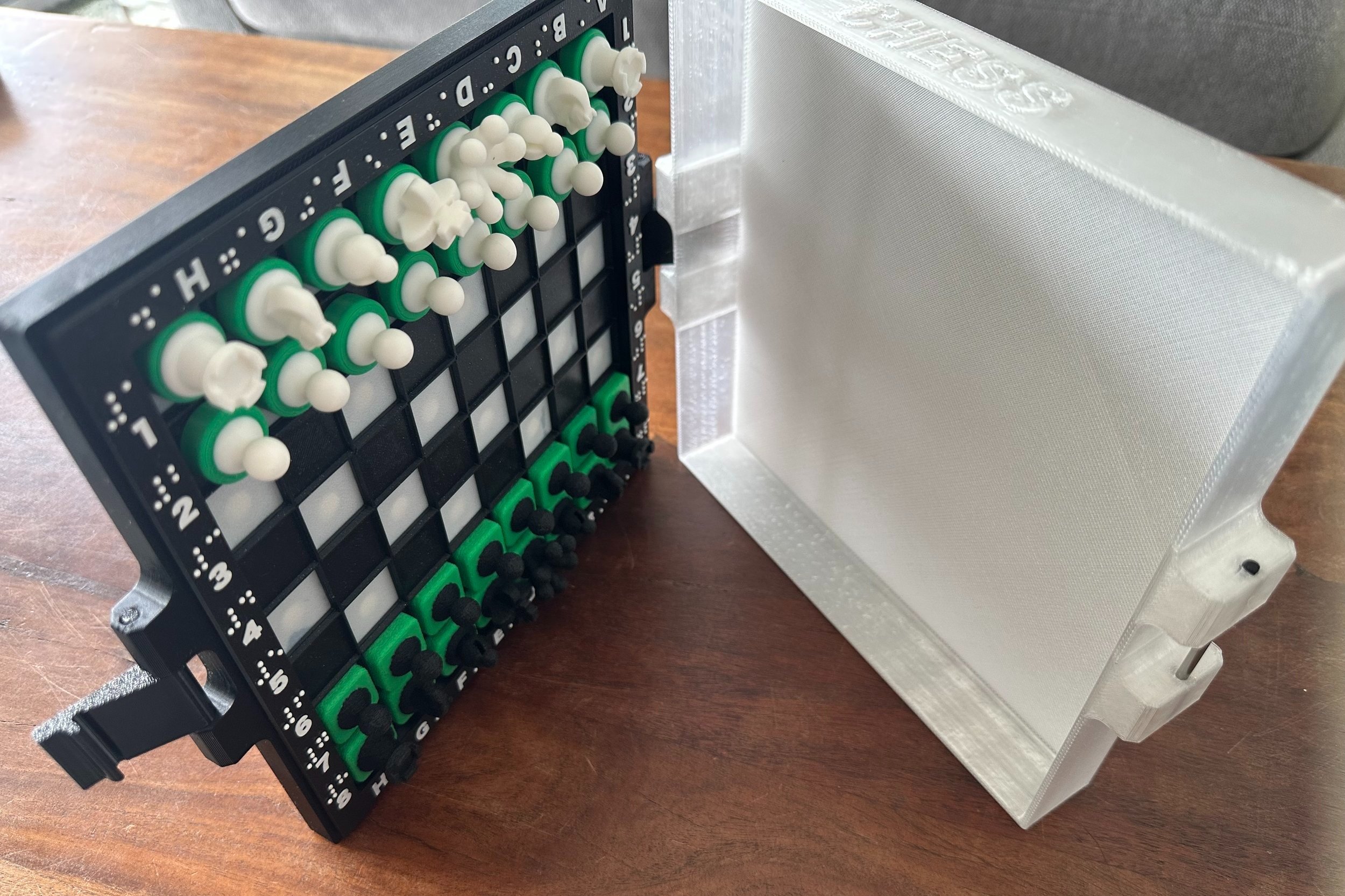 Open braille chessboard, shown on it's side with magnetic pieces attached to the board.