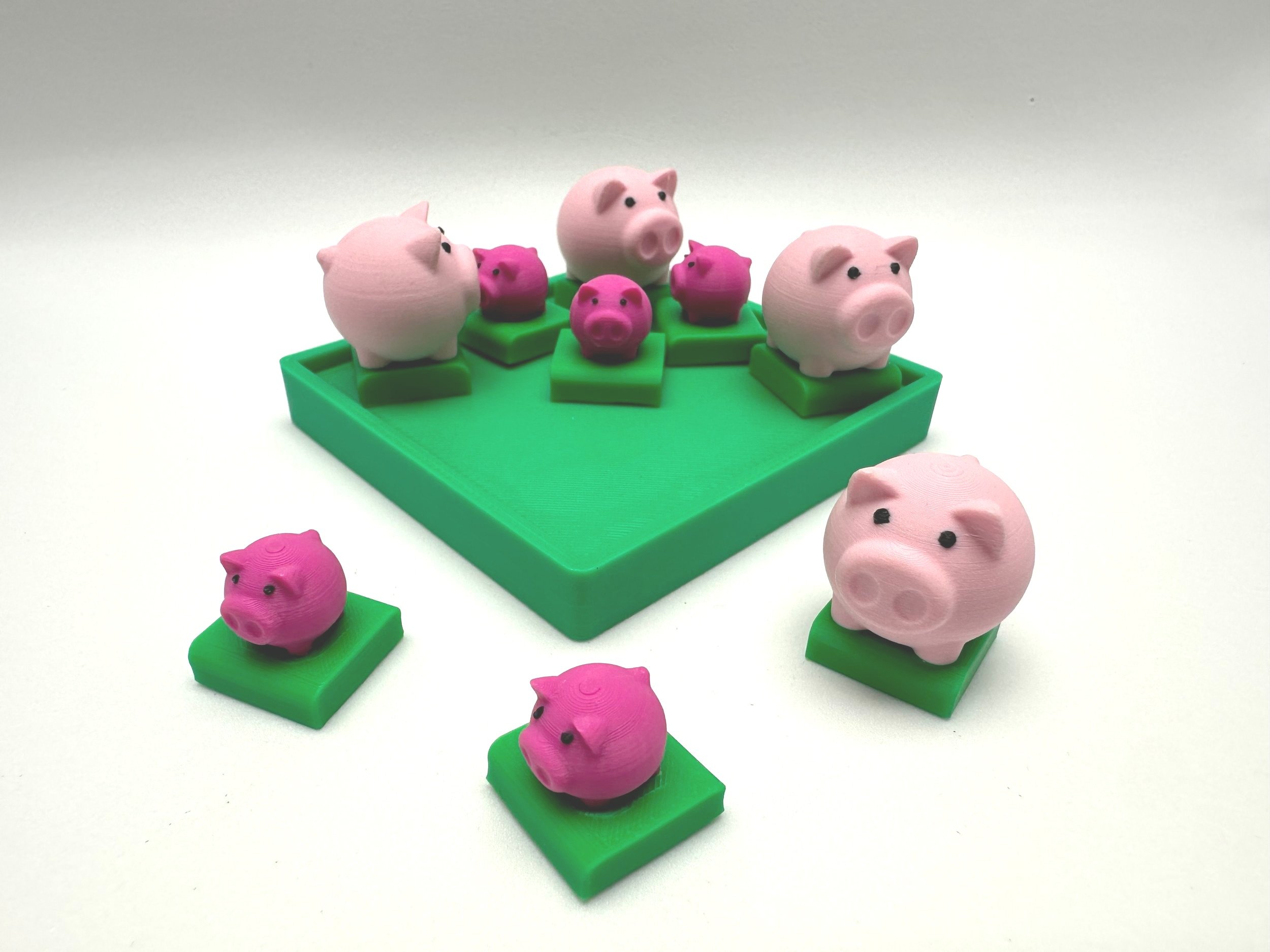 4 Large light pink piggy bank shaped pigs and 5 small dark pink pigs on green bases. Most of the pigs are on a green tray; the remaining 3 pigs on the table.